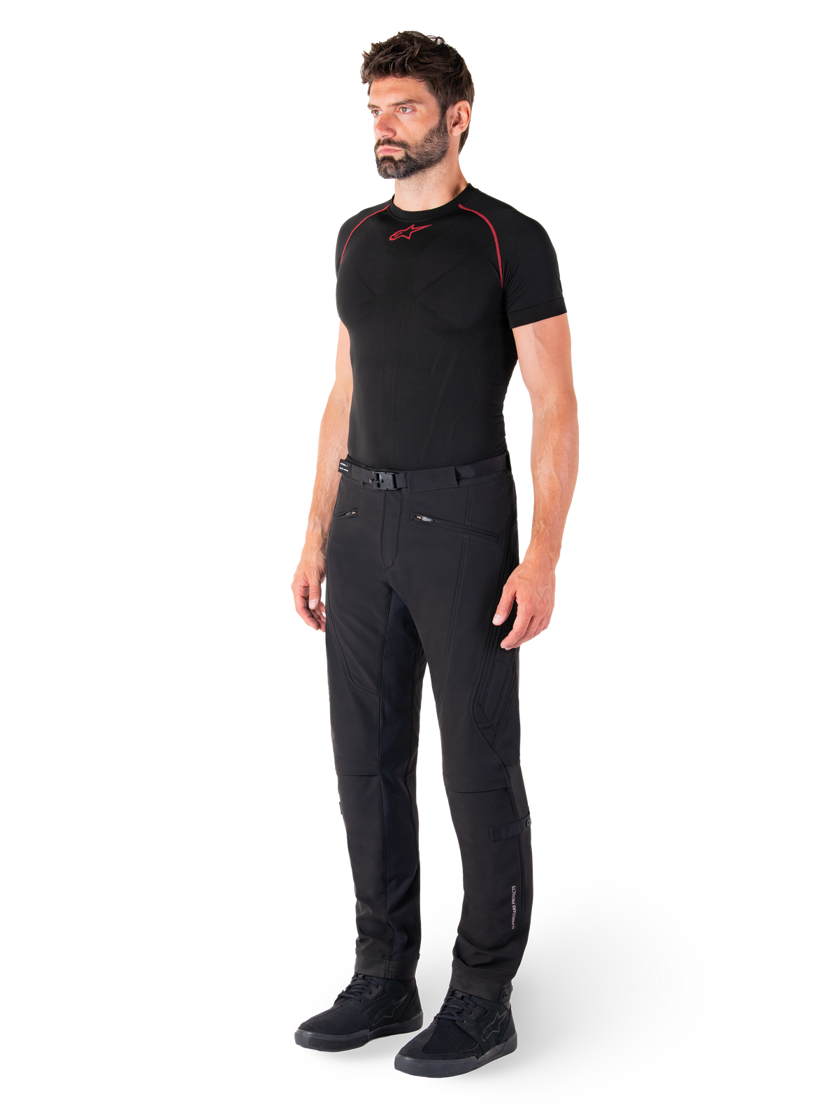 Pantaloni Alpinestars Alden, pantaloni da moto urban, nero, tessuto softshell vestibilità regular, indossati da un modello con base layer nero e scarpe da moto, con cintura in vita con chiusura magnetica e tasche con zip.