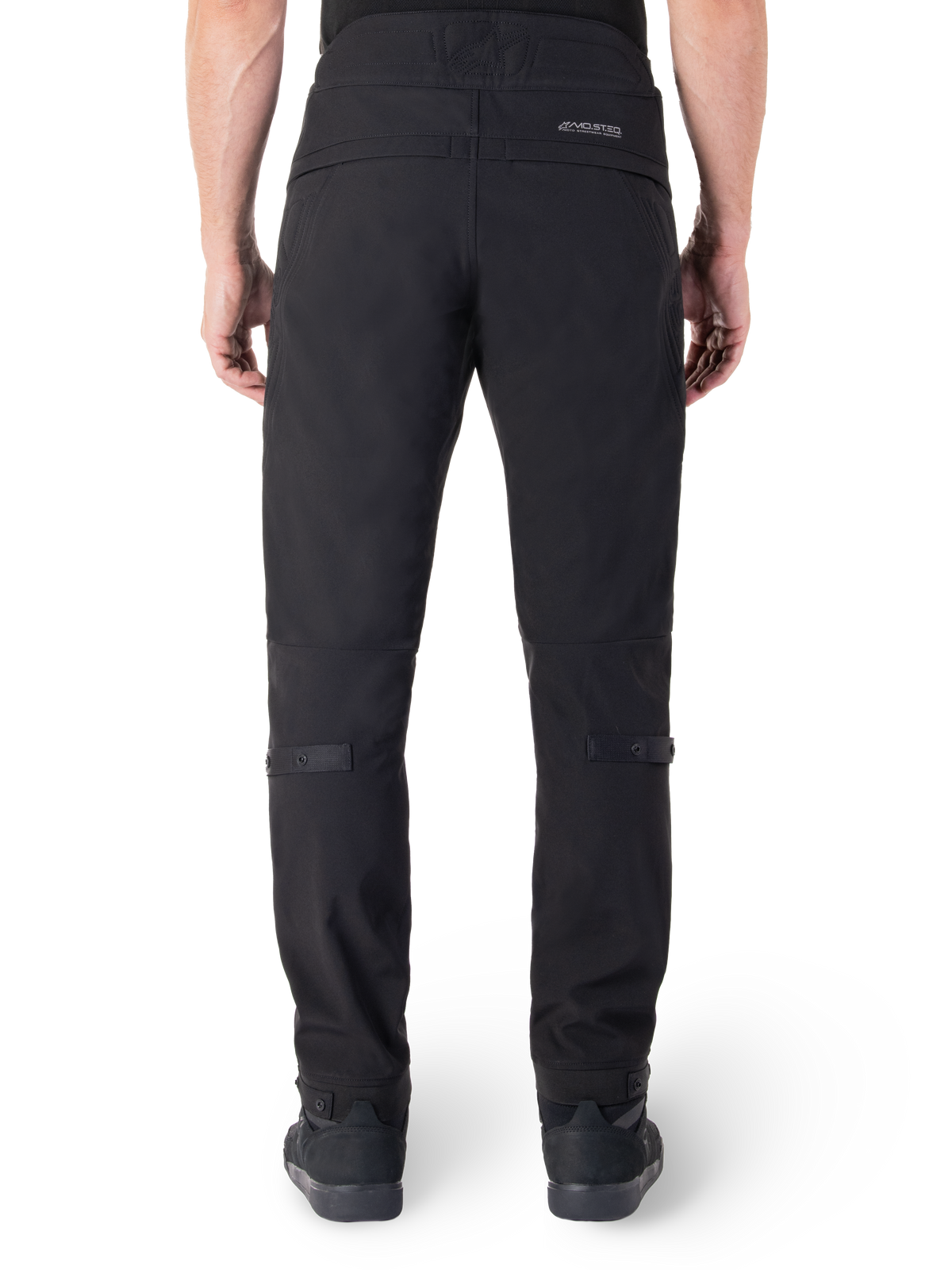 Pantaloni Alpinestars Alden, pantaloni da moto urbani neri, vista posteriore, con marchio MO.ST.EQ. riflettente sul carré posteriore, vestibilità aderente sotto il ginocchio e regolatori di volume con bottoni a pressione su polpacci e caviglie, design in tessuto tecnico ispirato allo streetwear.