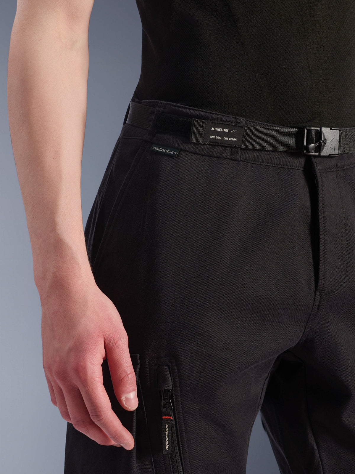 Alpinestars Flex-AST Cargo Pants, pantaloni da moto urbani, nero, vista ravvicinata della vita e della tasca laterale, cintura integrata con marchio Alpinestars, chiusura con fibbia, tasca con zip con tirazip logato, costruzione in tessuto tecnico per guida urbana