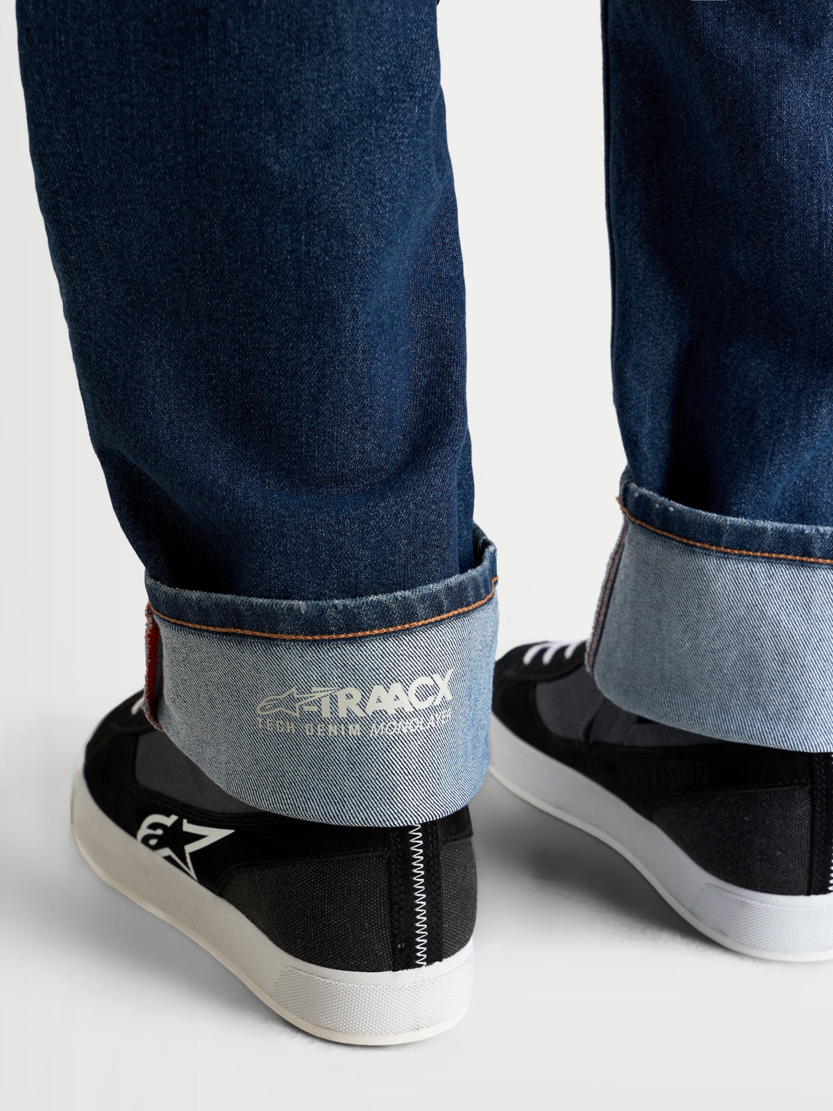 Alpinestars Flex Ast 8 Denim Pantaloni, pantaloni da moto in denim blu medio, vista ravvicinata dell'orlo risvoltato che mostra il marchio interno A-TRAACX in denim tecnico monostrato e la finitura con cimosa