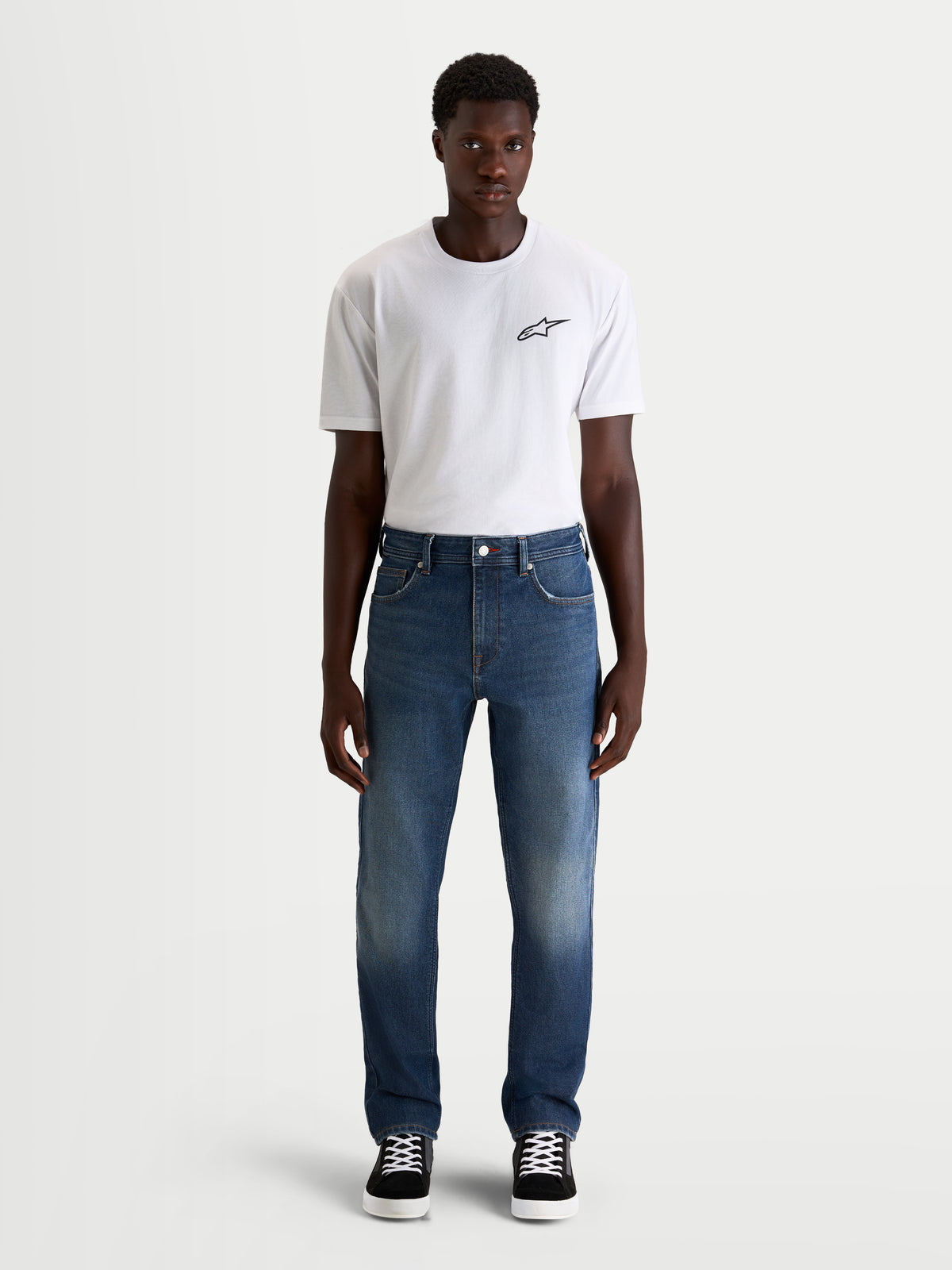 Alpinestars Flex Ast 8 Denim Pantaloni, jeans da moto urbani da uomo in blu medio, vestibilità dritta monostrato, indossati da un modello con t-shirt bianca, protezione certificata AA