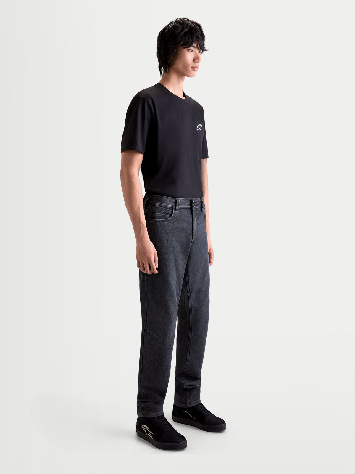 Alpinestars Flex Ast 7 Denim Pantaloni, jeans da moto urban contemporanei da uomo in nero slavato, vista laterale su un modello che indossa una maglietta nera e scarpe, costruzione in denim tecnico monostrato con certificazione AA