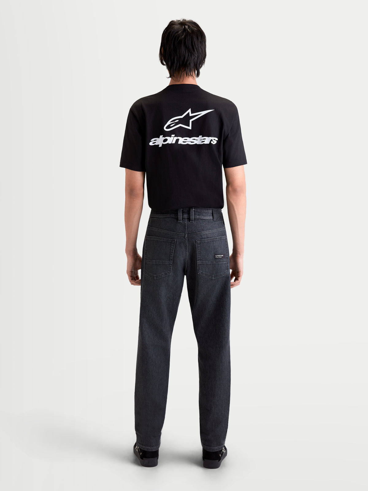 Alpinestars Flex Ast 7 Denim Pantaloni, jeans da moto urbani da uomo in nero slavato, vista posteriore con layout a cinque tasche e patch in pelle indossati da un modello