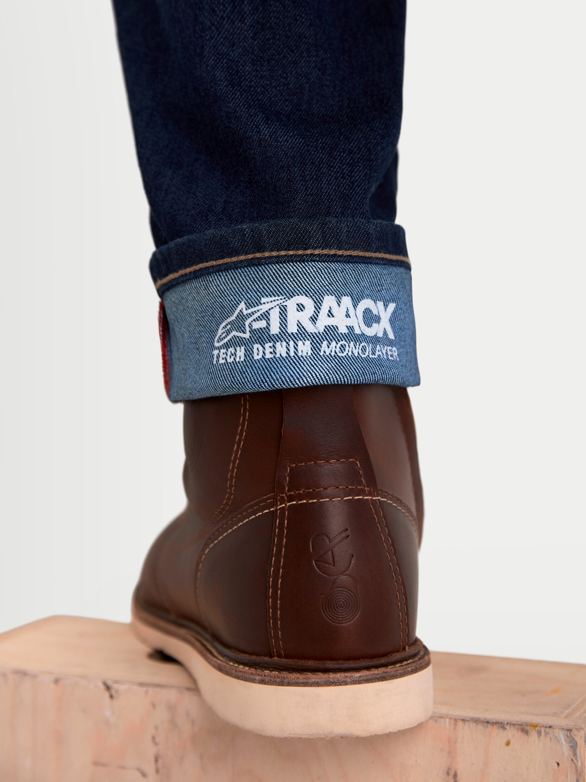 Alpinestars Flex Ast 7 Denim Pantaloni, jeans da moto urbani da uomo, blu scuro, primo piano dell'orlo risvoltato con il marchio A-TRAACX technical denim e stivali in pelle marroni