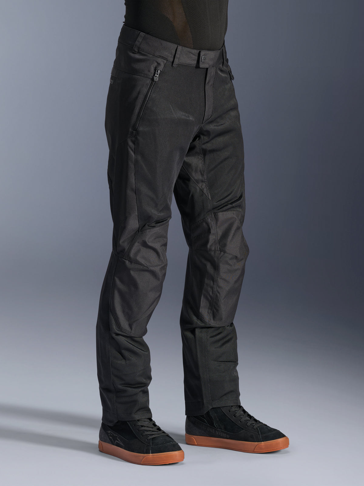 Alpinestars C-1 Air Pants, pantaloni da moto urban, nero, con pannelli in rete tecnica traspirante e costruzione in poliestere, indossati con sneaker nere, design pulito e funzionale per la guida in città.