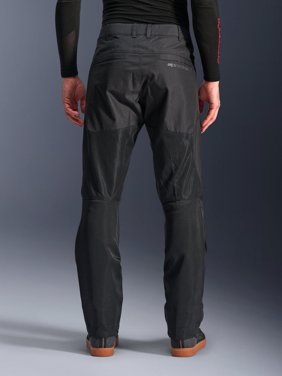 Alpinestars C-1 Air Pants, vista posteriore, nero, pantaloni da moto urbani in tessuto con ampi pannelli in mesh tecnica sul retro delle gambe per la ventilazione, design essenziale con logo discreto, indossati con base layer nero e scarpe da guida casual