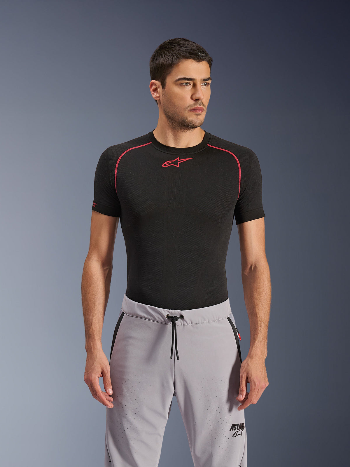 Alpinestars Aeroshell Airflow Pants, grigio medio, pantaloni da moto indossati con un base layer tecnico nero, con cosce traforate al laser, vita con coulisse e tasche con cerniera, stile di guida urbano sportivo.