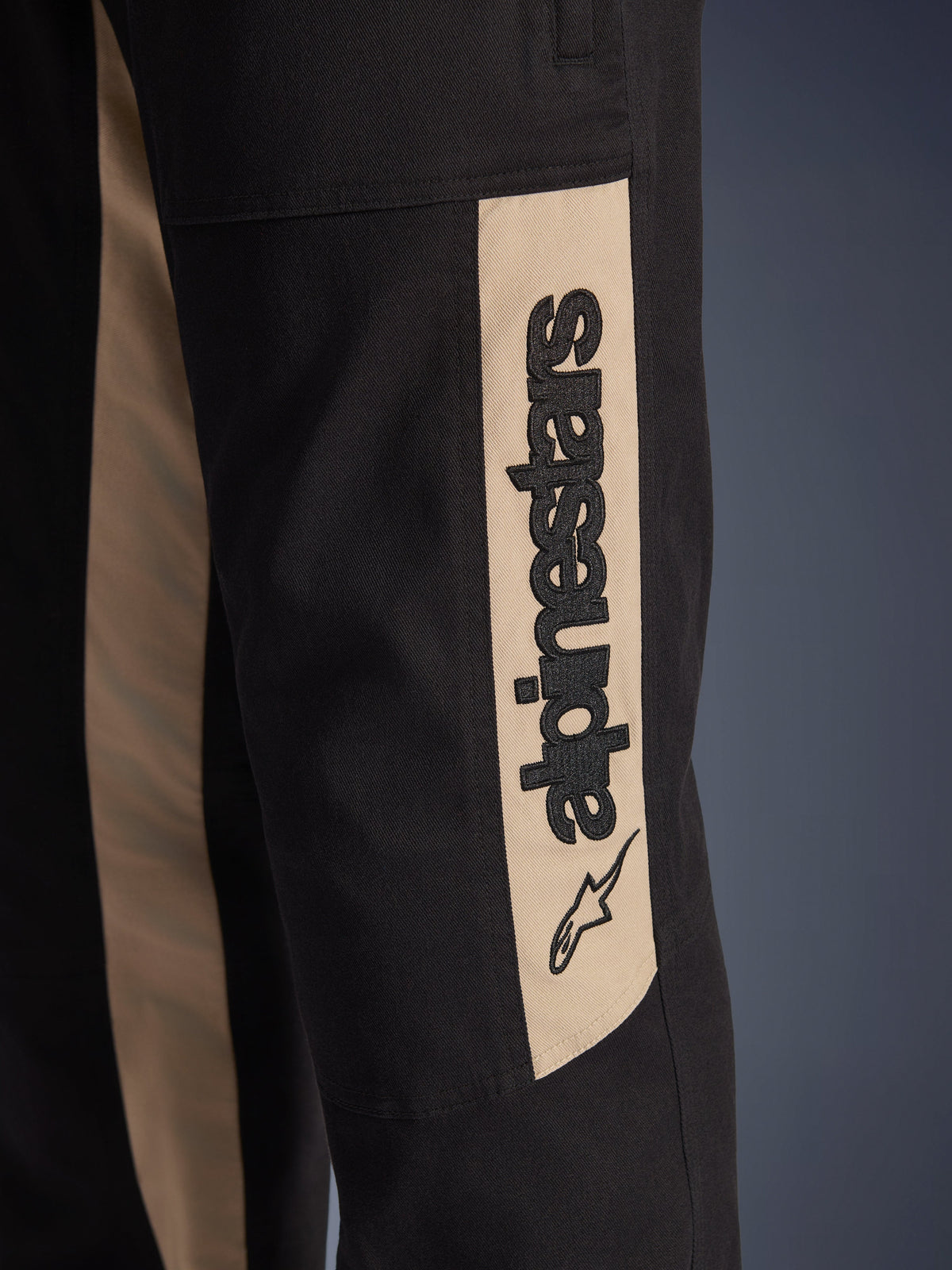 Pantaloni Alpinestars Flex-AST Canvas, dettaglio ravvicinato della gamba laterale, nero con inserto color alluminio, con logo Alpinestars verticale e icona a stella, in resistente twill di policotone per la guida urbana.