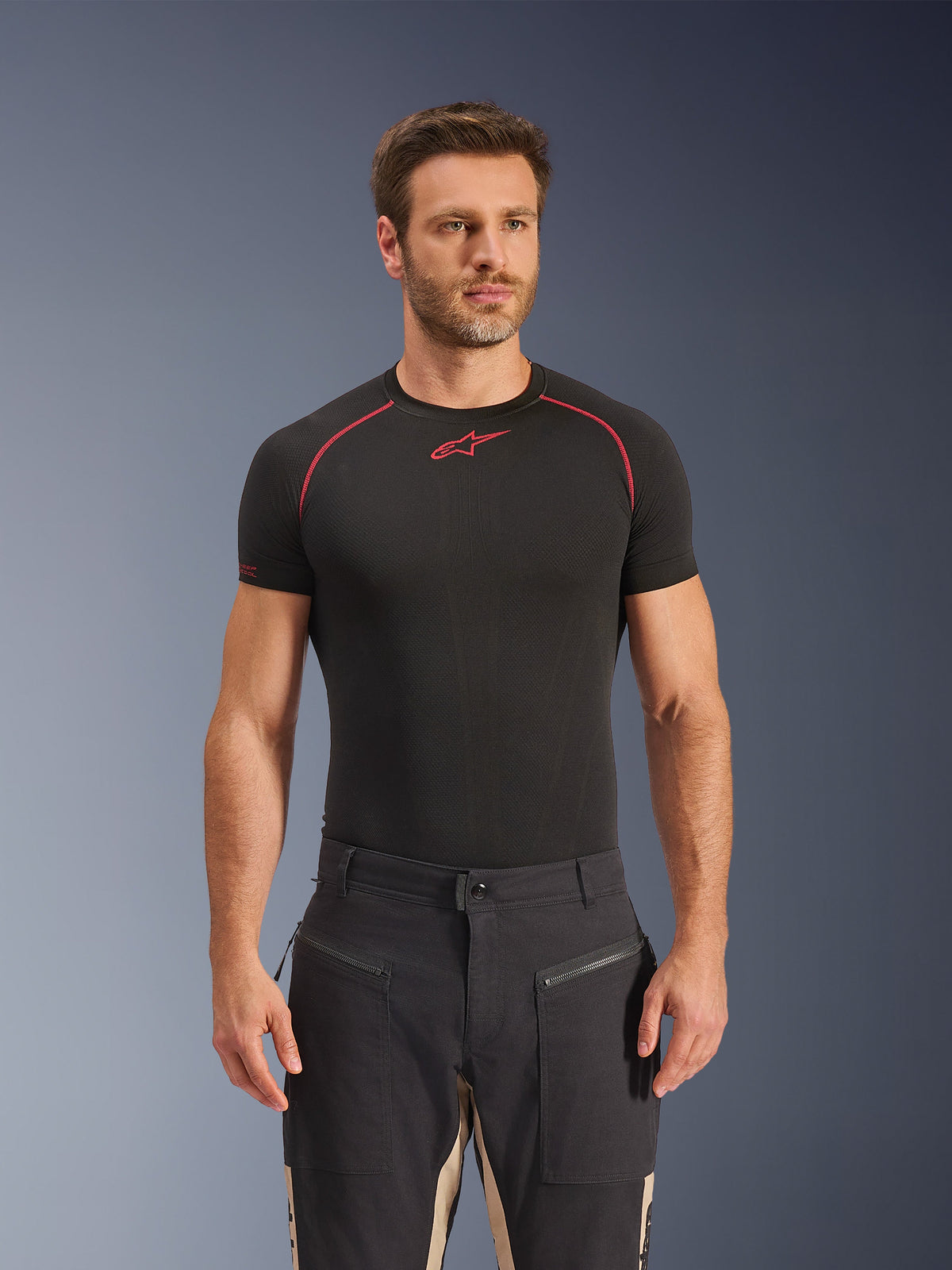 Pantaloni Alpinestars Flex-AST Canvas in Black Aluminum, pantaloni da moto urbani con design workwear utilitaristico, tasche anteriori con cerniera e pannelli a contrasto color sabbia all'interno delle gambe, indossati da un modello con una t-shirt base layer nera.