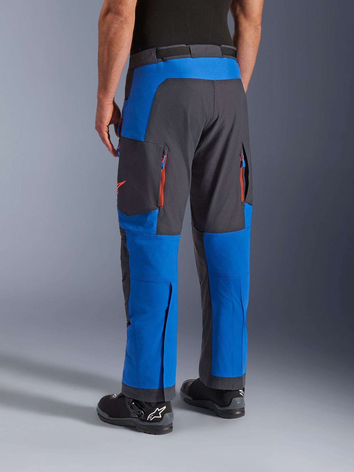 Pantaloni Alpinestars Maxdura Dual, Blu Royal e Deep Gray, vista posteriore con tasche con zip e zone di ventilazione, design sopra-stivale indossato con stivali Alpinestars neri, abbigliamento resistente per guida adventure e dual-sport