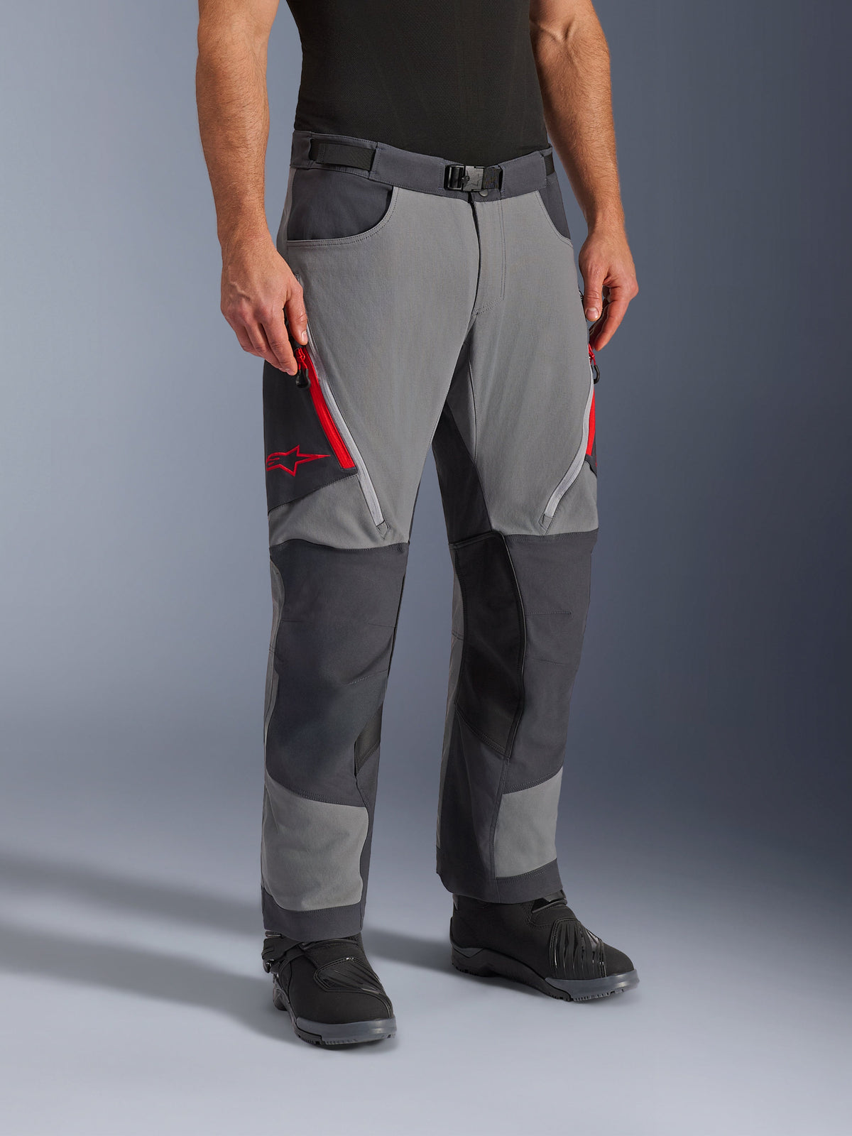 Alpinestars pantaloni Maxdura Dual in grigio scuro e grigio intenso, pantaloni da moto adventure-touring con prese d'aria con zip rosse sulle cosce e logo a stella, pannelli scuri rinforzati sulle ginocchia, abbinati a stivali da moto neri