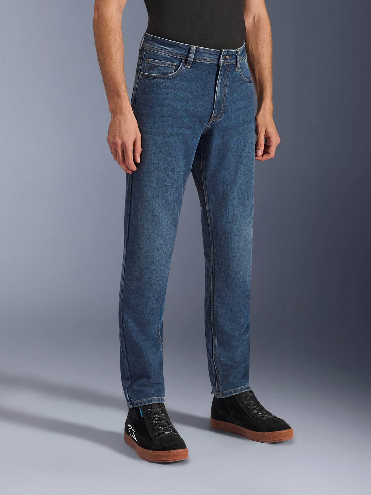 Pantaloni Alpinestars Flex-AST 5 Denim, jeans da moto color indaco lavato, vestibilità affusolata regolare, indossati con sneaker alte nere e una maglietta nera, abbigliamento da moto urban casual dall'aspetto denim classico