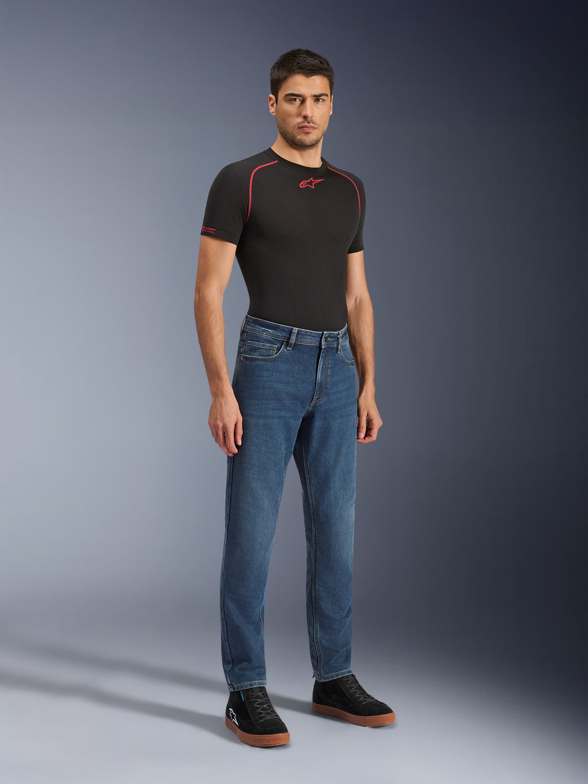 Alpinestars Flex-AST 5 Denim Pants - Short, Indigo Washed, jeans da moto urban con vestibilità affusolata, indossati da un modello con maglia nera aderente e sneaker nere, stile denim classico per l'uso urbano quotidiano
