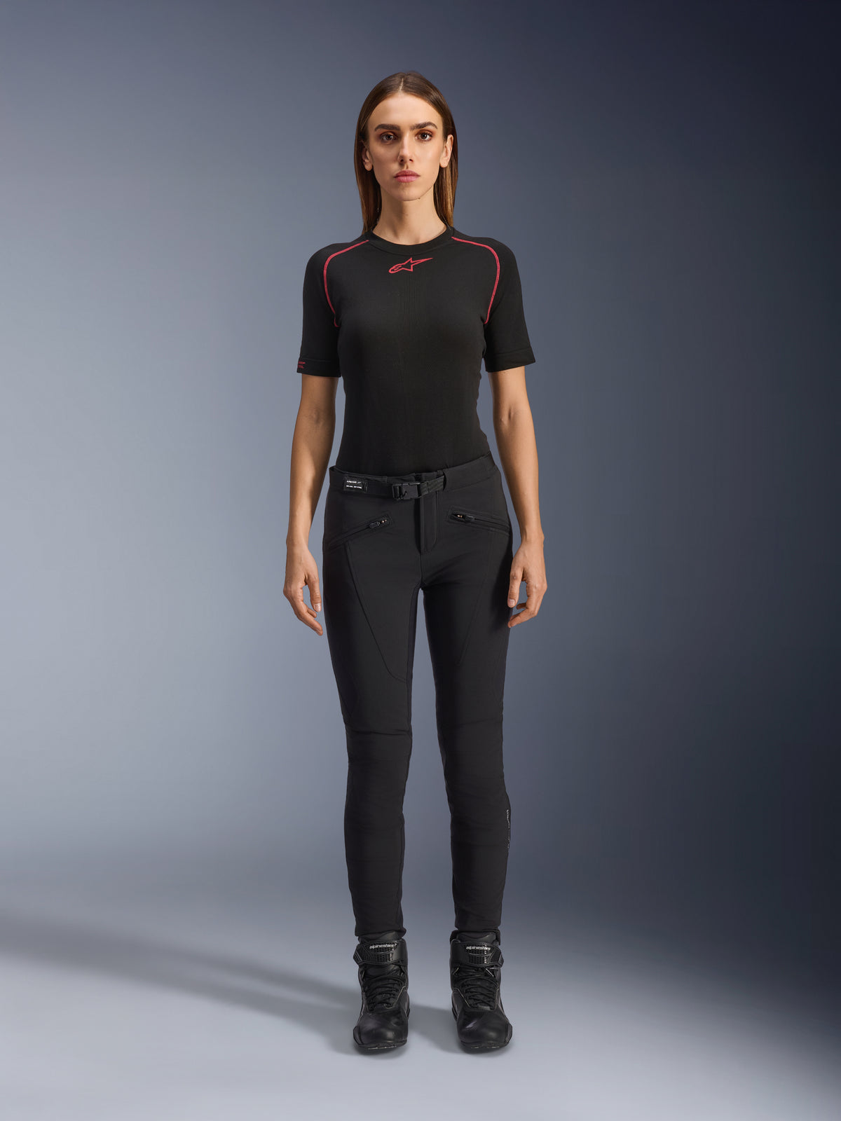 Pantaloni Alpinestars Alamosa Donna, pantaloni da moto neri slim-fit, indossati da una modella in posizione frontale, con tasche anteriori dotate di zip e cintura in vita integrata, stile minimalista ispirato allo streetwear per la guida urbana