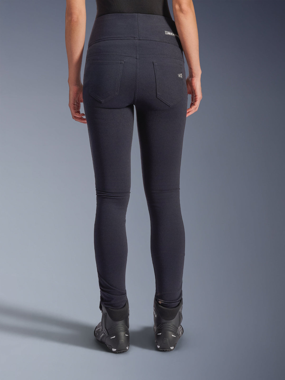 Alpinestars Stella Flex-AST Leggings, pantaloni da moto urbani, nero, vista posteriore con vestibilità skinny a vita alta, due tasche posteriori funzionali con branding discreto, materiale tessile elasticizzato, indossati con scarpe da moto nere.