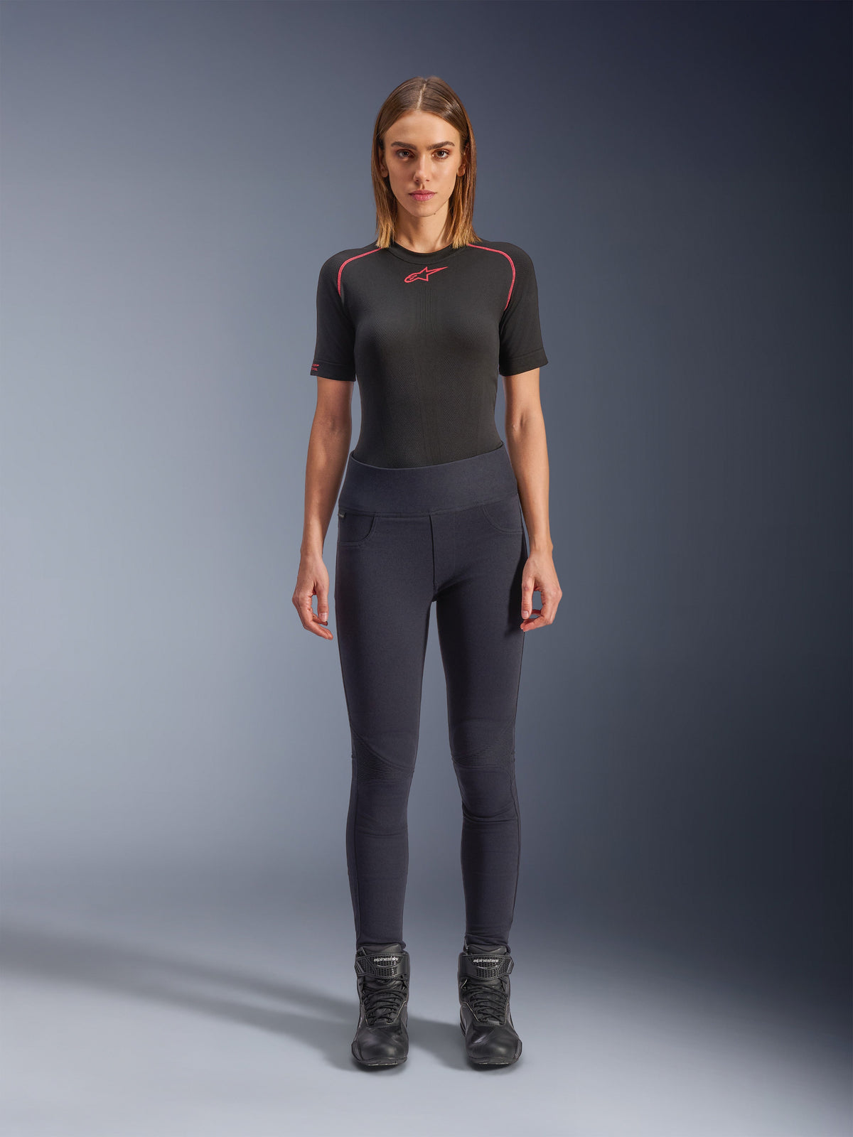 Alpinestars Stella Flex-Ast Leggings, leggings da moto da donna, nero, indossati con top a maniche corte nero con dettagli rossi e stivali da moto neri, abbigliamento da guida urban contemporaneo slim-fit, vista frontale