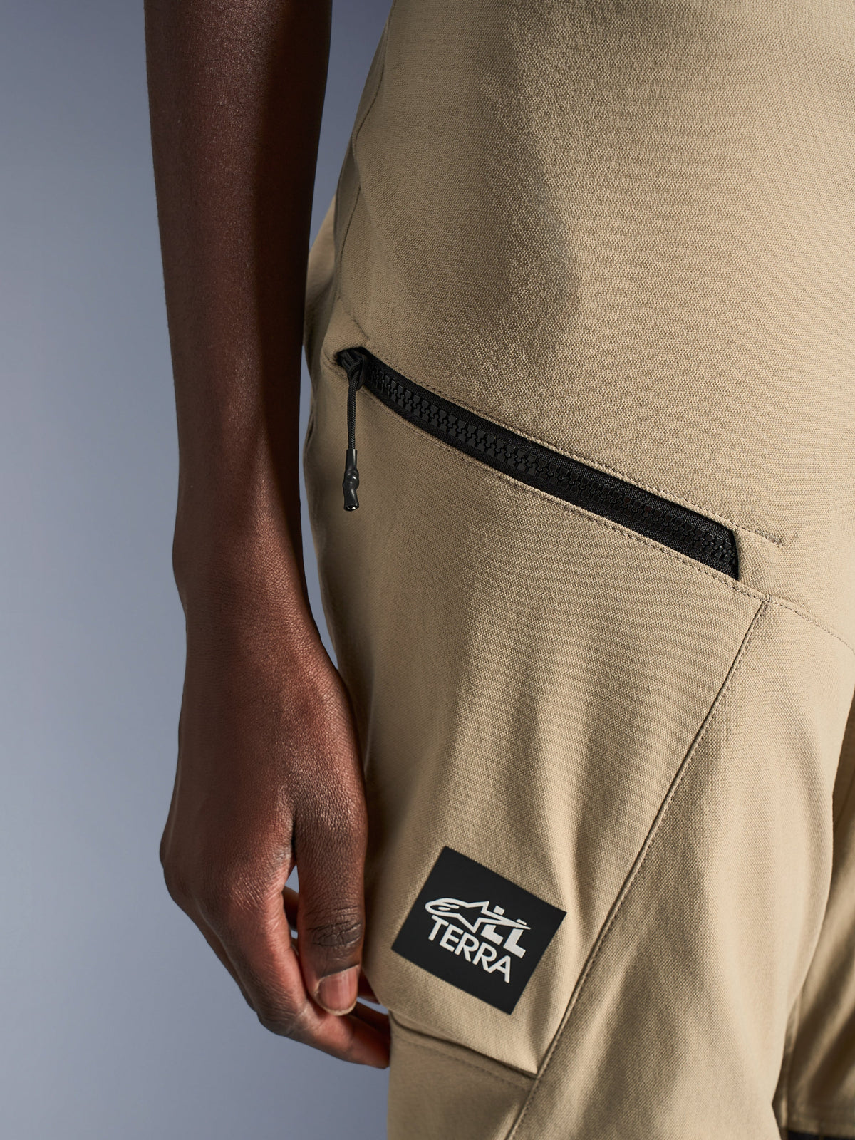 Alpinestars Stella Flex-AST Explorer Pants, pantaloni da moto da donna, sabbia, dettaglio ravvicinato della tasca cargo con cerniera e patch nera con logo ALL TERRA, costruzione in tessuto ripstop resistente per l'adventure touring