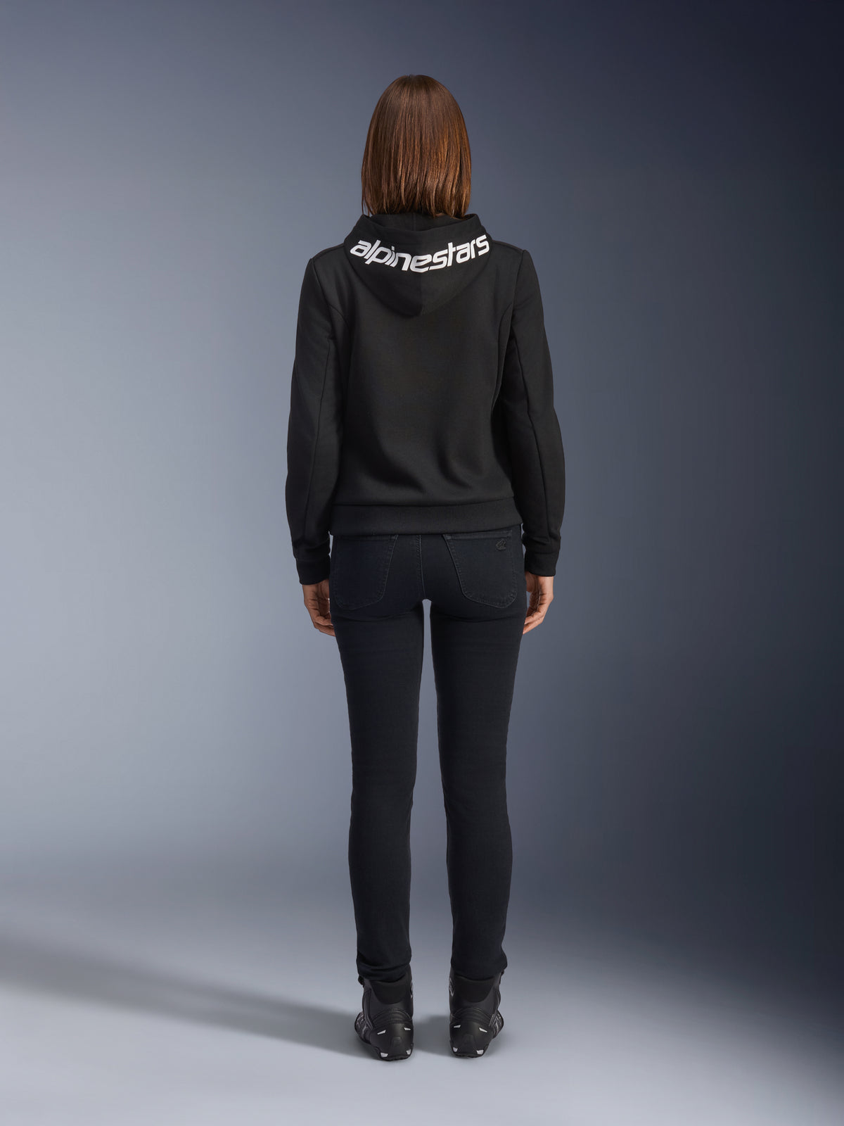 Daisy V3 Jeans da moto da donna, Black Rinse, pantaloni slim fit, vista posteriore con vita alta e silhouette femminile, abbinati a una felpa nera Alpinestars e stivali da moto neri, abbigliamento da guida urban casual