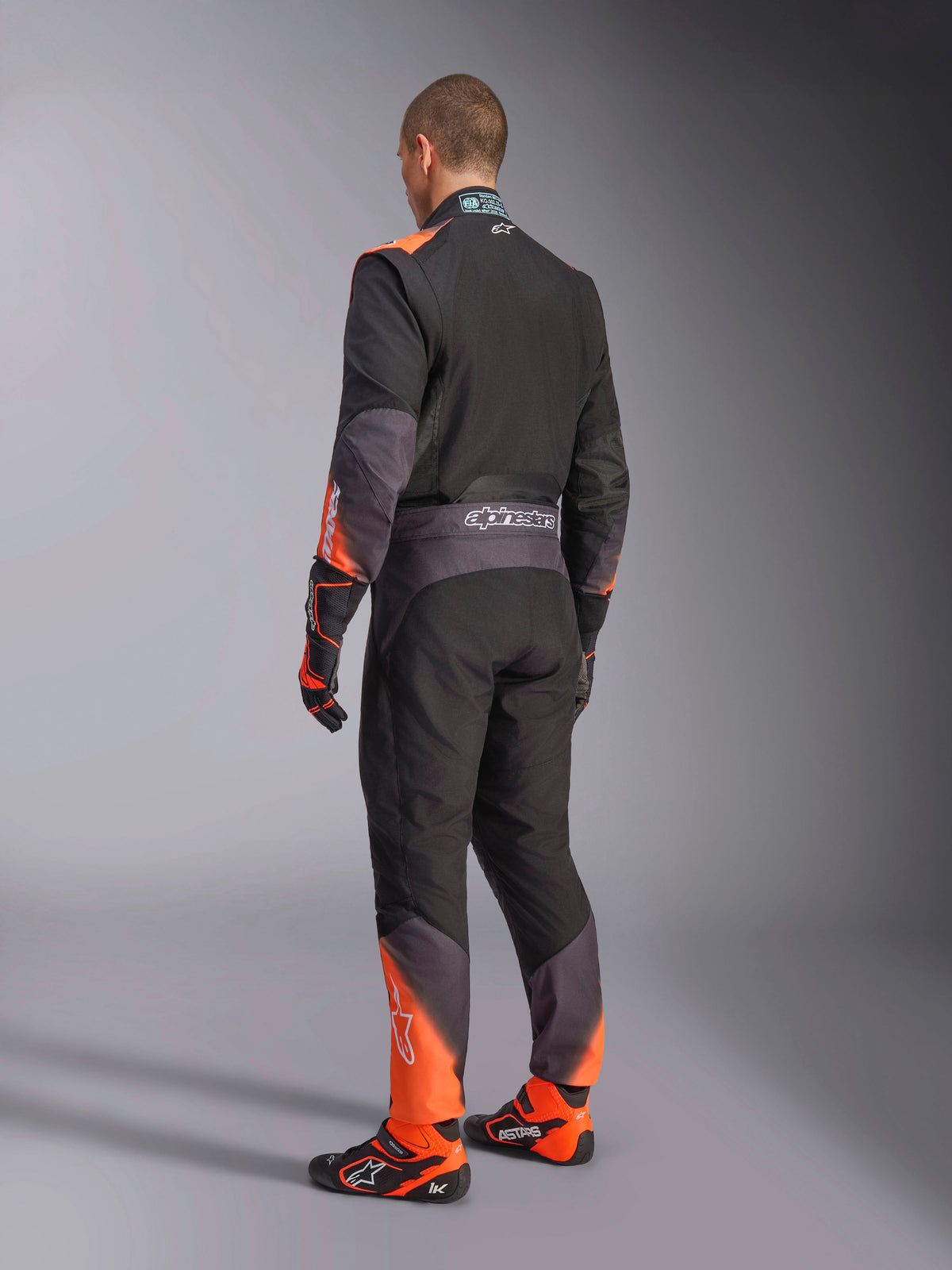 Alpinestars tuta KMX-5 V3 per karting da uomo, vista posteriore, nera e arancione fluo, certificata FIA 8877-2022.