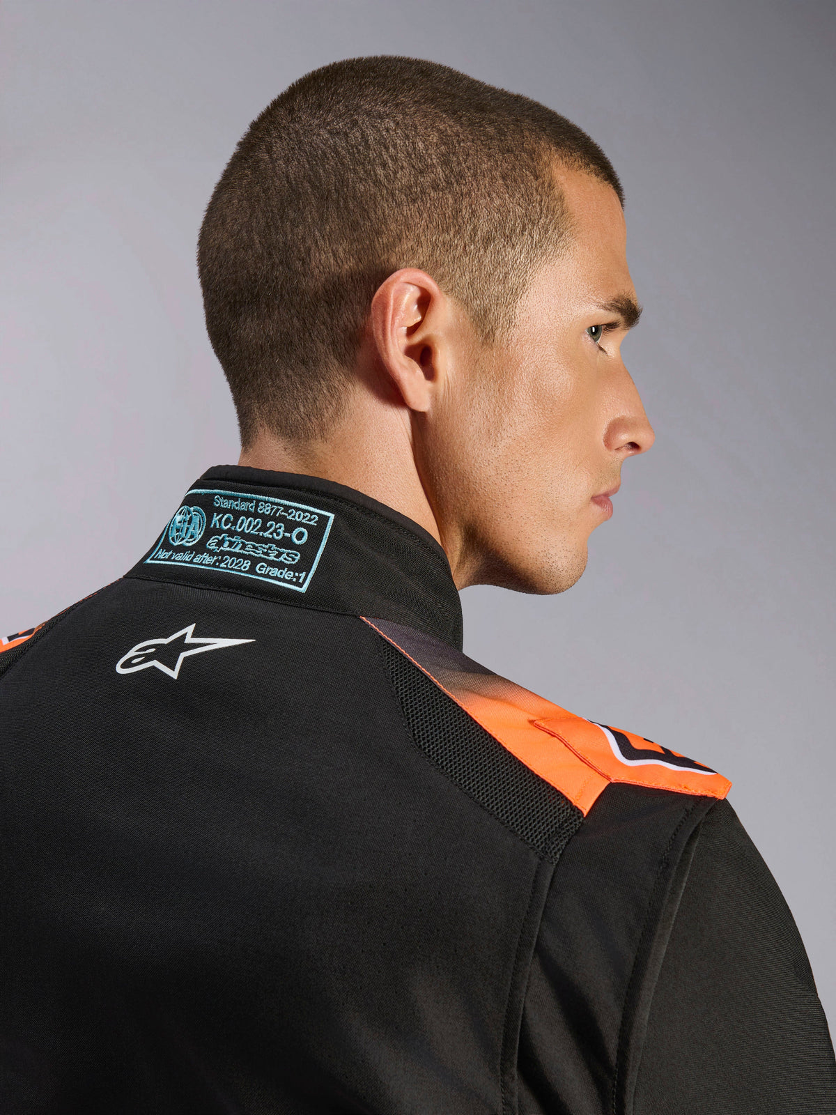 Alpinestars tuta KMX-5 V3, tuta da karting per uomo, nera e arancione fluo, certificata FIA 8877-2022 Grado 1, dettaglio colletto con logo bianco e mesh traspirante.