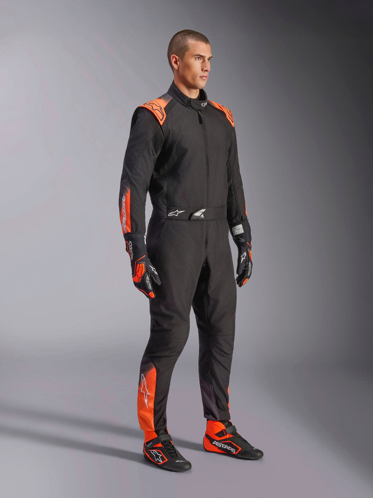 Alpinestars Tuta KMX-5 V3, tuta da karting da uomo, nero e arancione fluo, certificata FIA Grado 1, indossata da un modello.