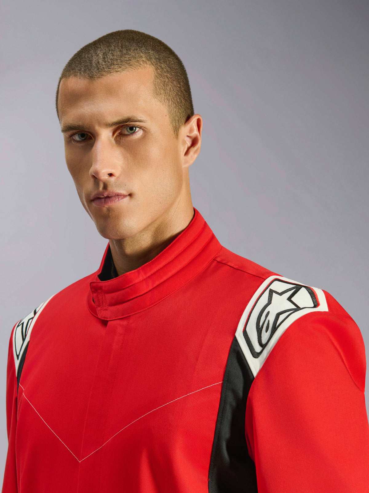 Alpinestars Kart Indoor V2 Suit in rosso, ritratto ravvicinato di un modello che indossa la tuta, che mette in risalto il colletto ergonomico e i dettagli bianchi e neri sulle spalle con il logo Alpinestars.