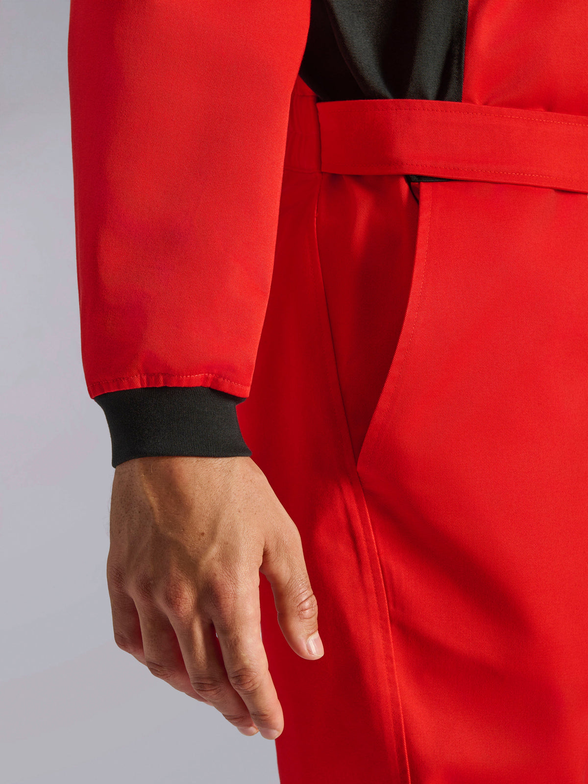 Alpinestars Kart Indoor V2 Suit, tuta da kart rossa, primo piano che mostra il polsino in maglia nero, la cintura regolabile in vita e il resistente materiale in twill a strato singolo