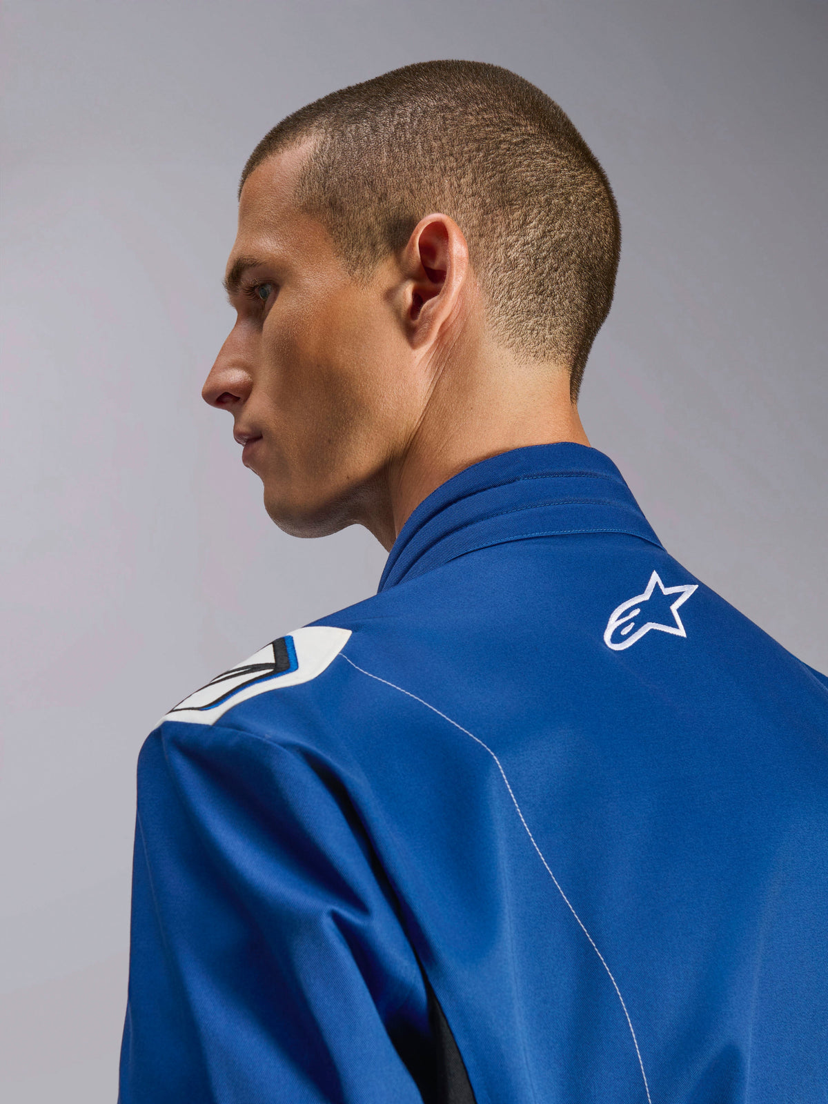 Alpinestars Kart Indoor V2 Suit, tuta da kart blu, primo piano del profilo laterale del colletto ergonomico e della parte superiore della schiena con logo a stella bianco, con design delle spalle ispirato alla Formula 1 e costruzione in twill di policotone resistente.