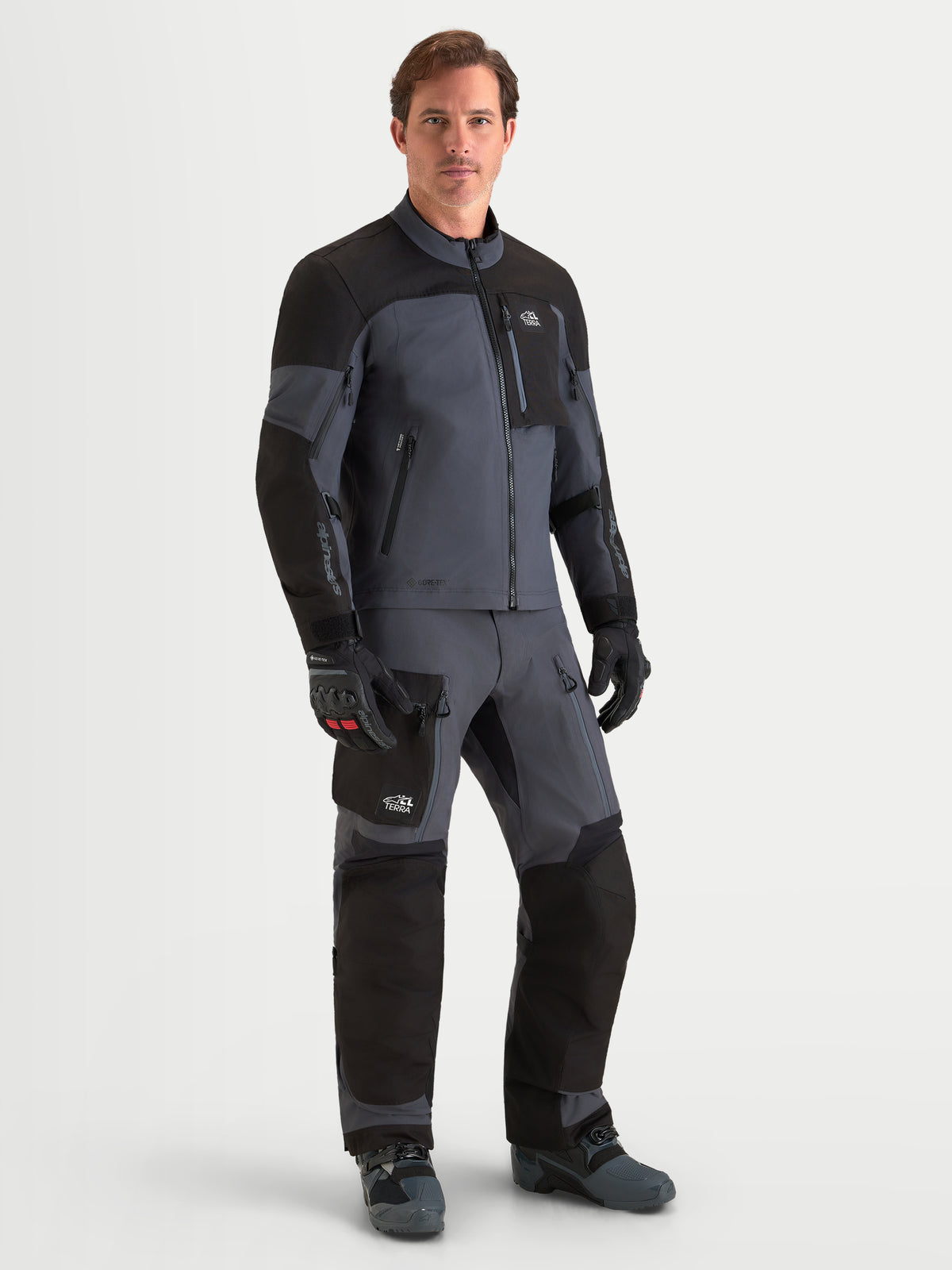 Alpinestars Arenis Gore-Tex Gear Set, giacca e pantaloni da moto adventure da uomo in nero e grigio scuro, vista frontale su un modello che indossa l'abbigliamento coordinato