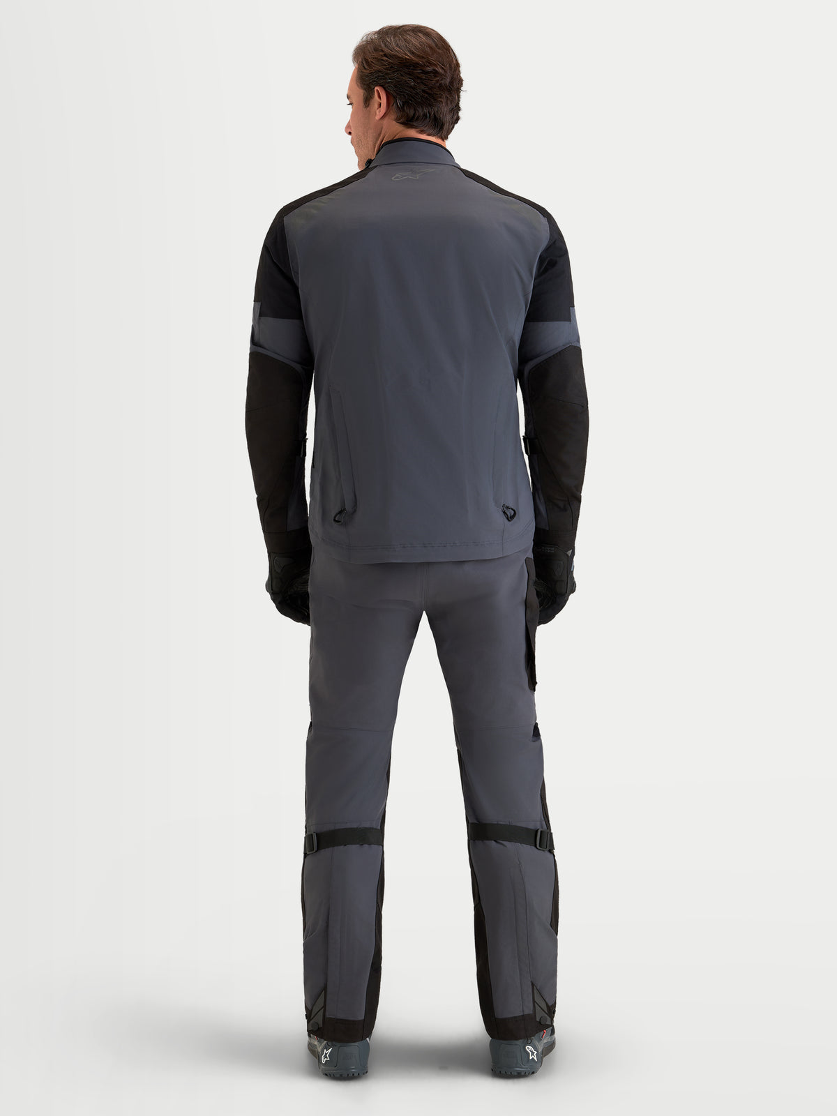Alpinestars Arenis Gore-Tex Gear Set, completo da moto adventure da uomo in grigio e nero, vista posteriore su un modello che indossa abbigliamento impermeabile per tutte le terre