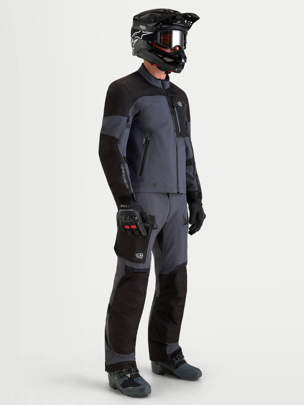 Alpinestars Arenis Gore-Tex Gear Set, completo da moto adventure da uomo in nero e grigio scuro, vista laterale su un modello che indossa abbigliamento impermeabile all-terrain e casco