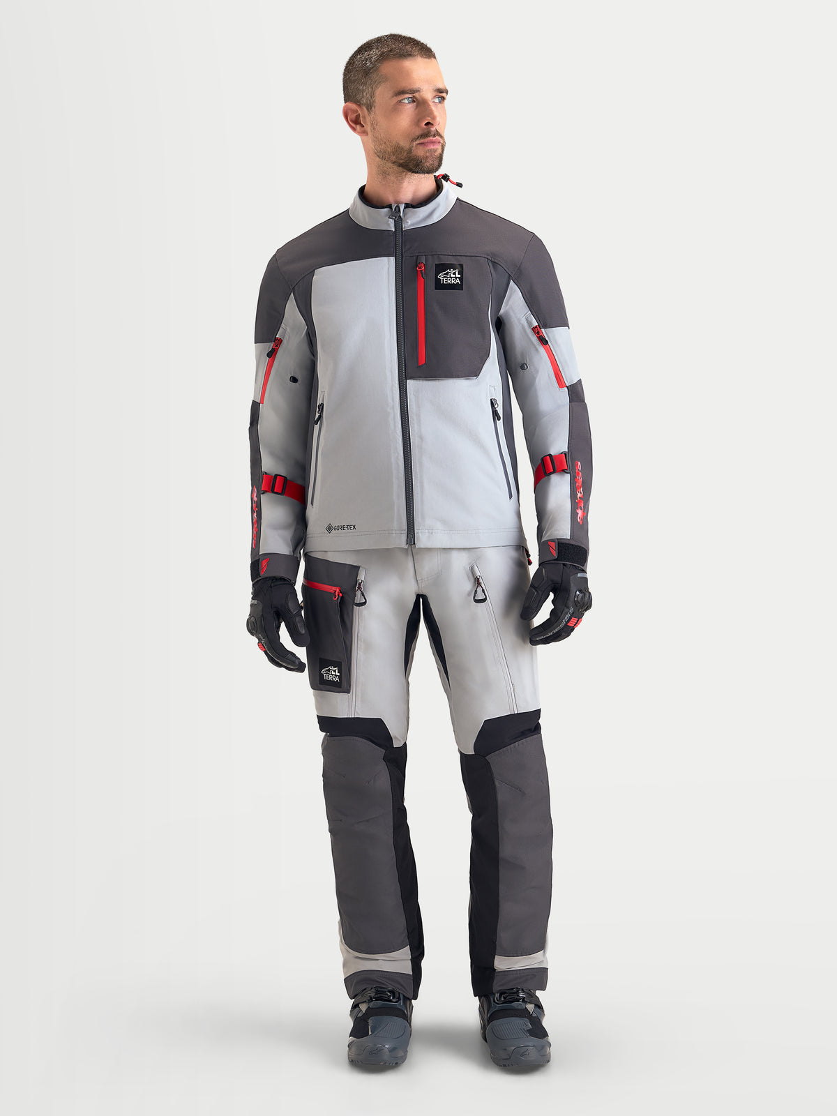 Alpinestars Arenis Gore-Tex Gear Set, completo da moto adventure touring da uomo in grigio chiaro, grigio scuro e rosso, vista frontale su un modello che indossa abbigliamento impermeabile all-terrain