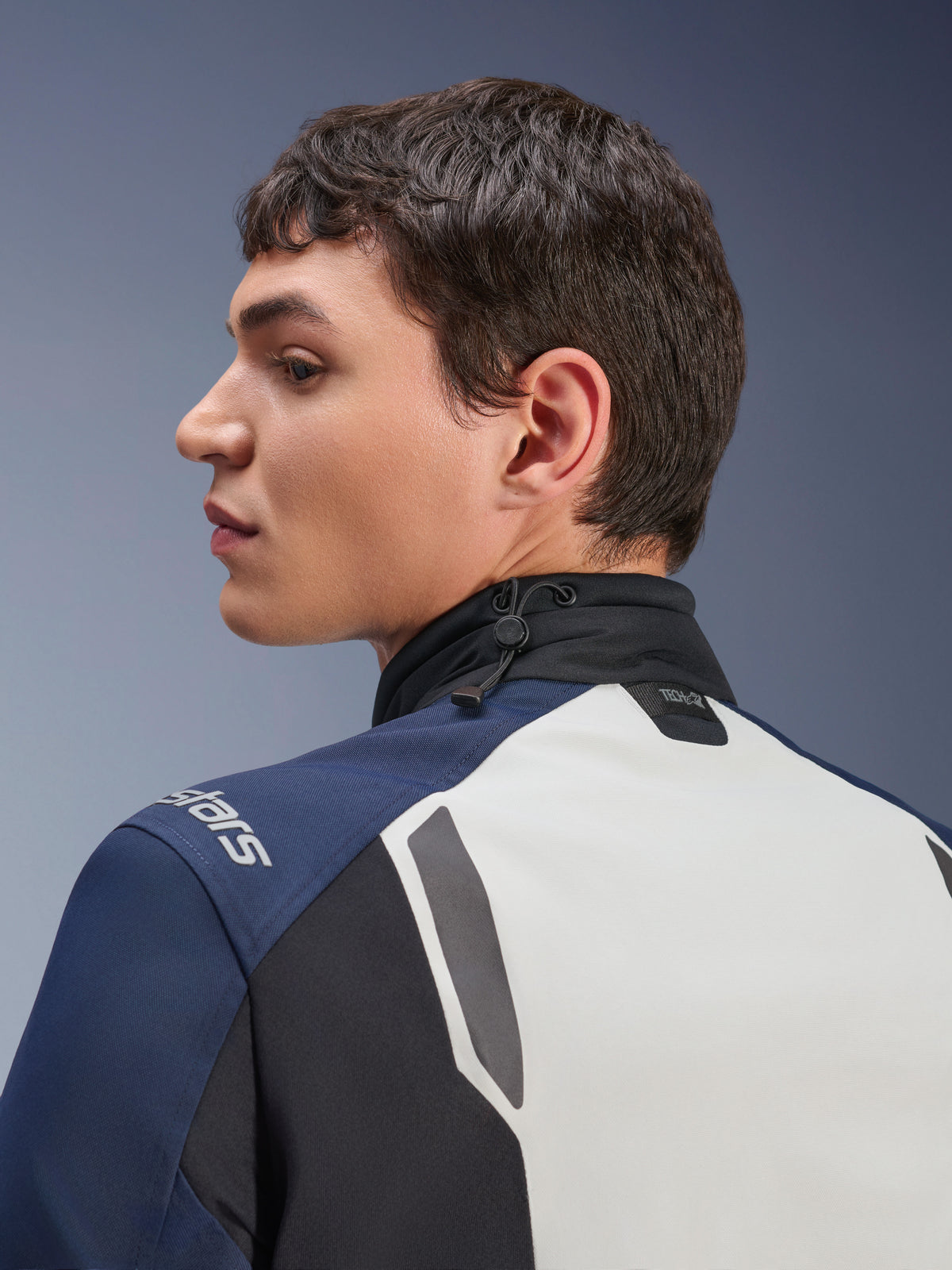 Giacca Alpinestars ST-7 2L GORE-TEX, vista ravvicinata di profilo della zona posteriore e del collo, grigio ghiaccio, blu scuro e nero, con colletto regolabile tramite cordino elastico e marchio Tech-Air, giacca da moto premium per adventure touring.