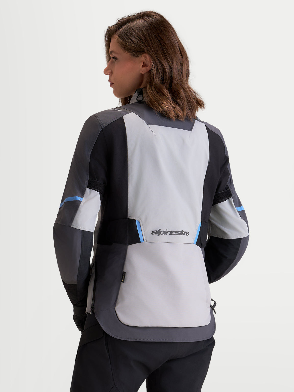 Alpinestars Stella St 7 V 2 2 L Gore Tex Giacca, giacca da moto adventure da donna in grigio medio, grigio scuro e nero, vista posteriore con struttura impermeabile e logo Alpinestars indossata da una modella