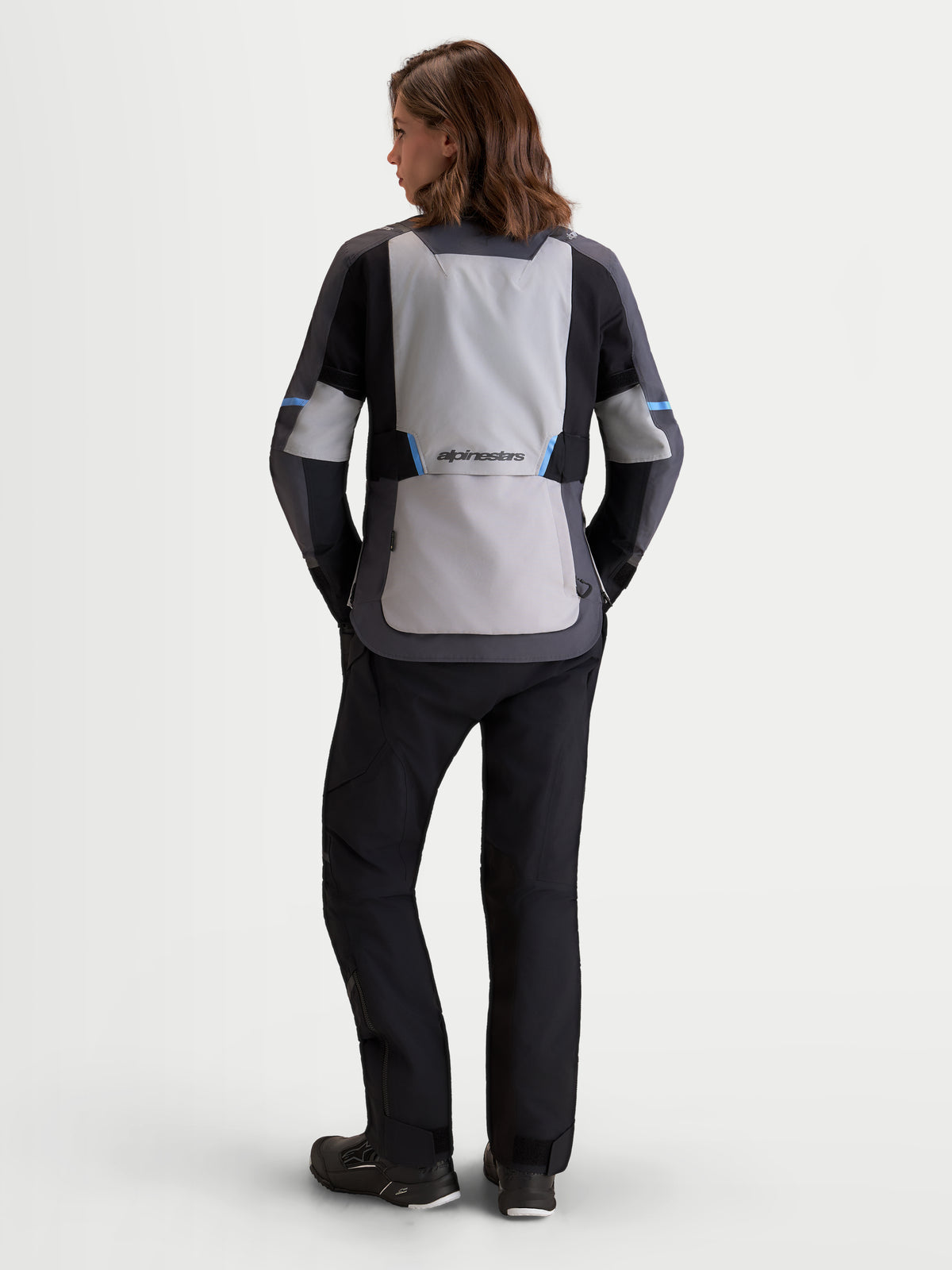 Alpinestars Stella ST-7 V2 2L Gore-Tex Giacca, giacca da moto adventure da donna in grigio medio, grigio scuro e nero, vista posteriore su una modella che mostra la struttura in tessuto impermeabile e il pannello posteriore ergonomico