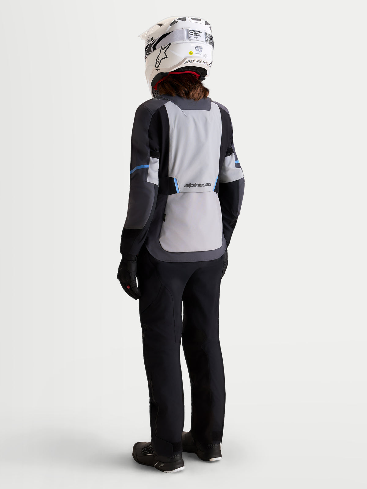 Alpinestars Stella ST-7 V2 2L Gore-Tex Giacca, giacca da moto adventure da donna in grigio medio, grigio scuro e nero, vista posteriore con modella che indossa equipaggiamento coordinato e casco, struttura in tessuto impermeabile