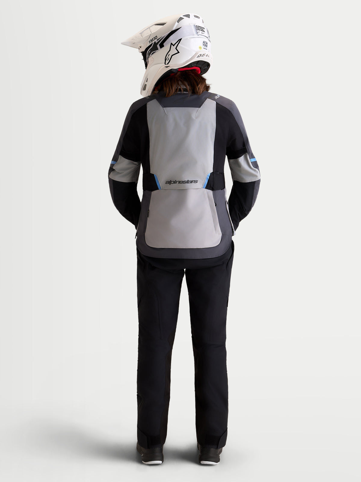 Alpinestars Stella ST-7 V2 2L Gore-Tex Giacca, giacca da moto adventure da donna in grigio medio, grigio scuro e nero, vista posteriore con modello che indossa equipaggiamento coordinato e casco