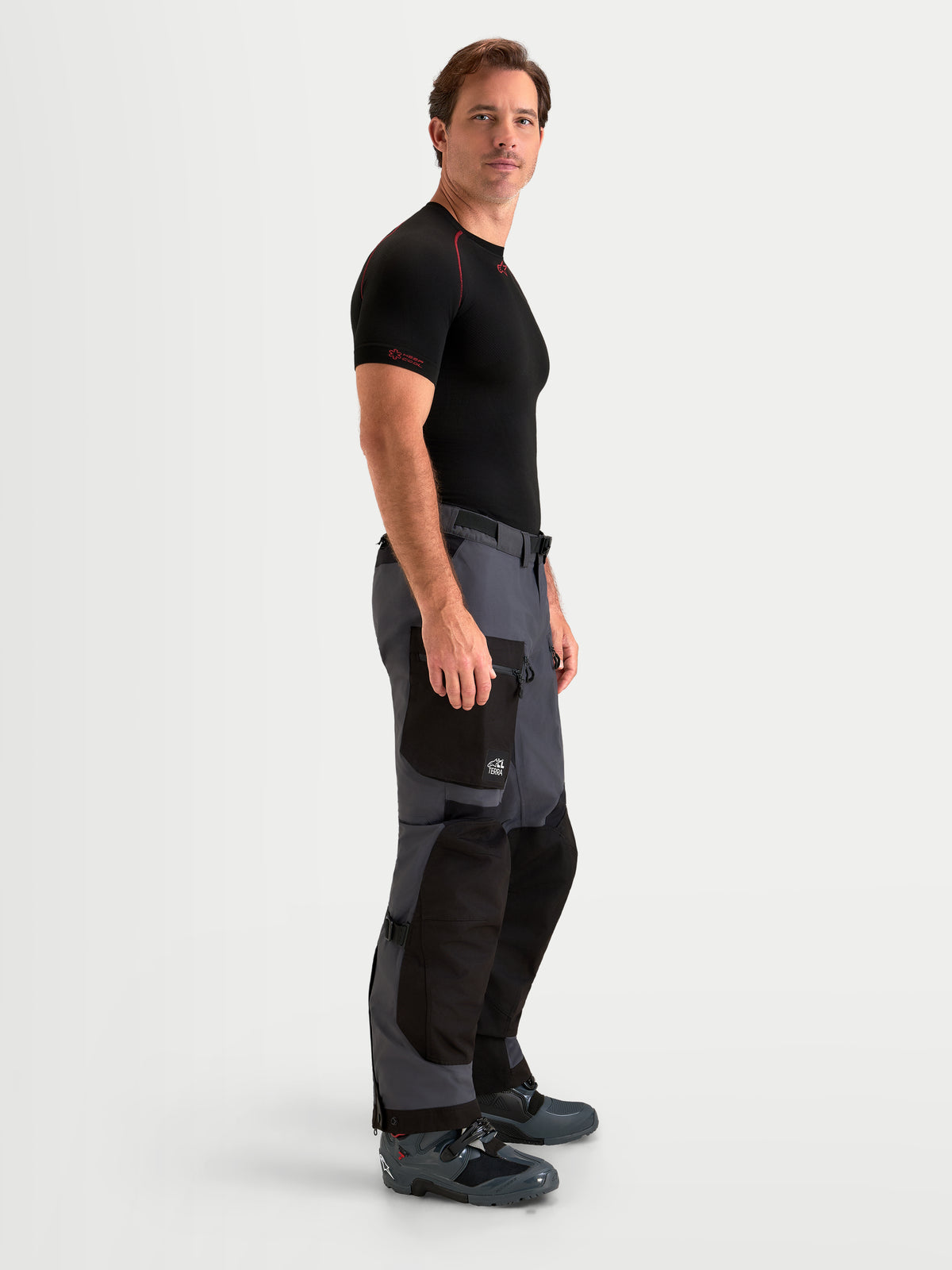 Alpinestars Arenis Gore-Tex Pantaloni, pantaloni da moto adventure da uomo in nero e grigio scuro, vista laterale indossati da un modello che mostra la struttura in tessuto impermeabile e la tasca cargo
