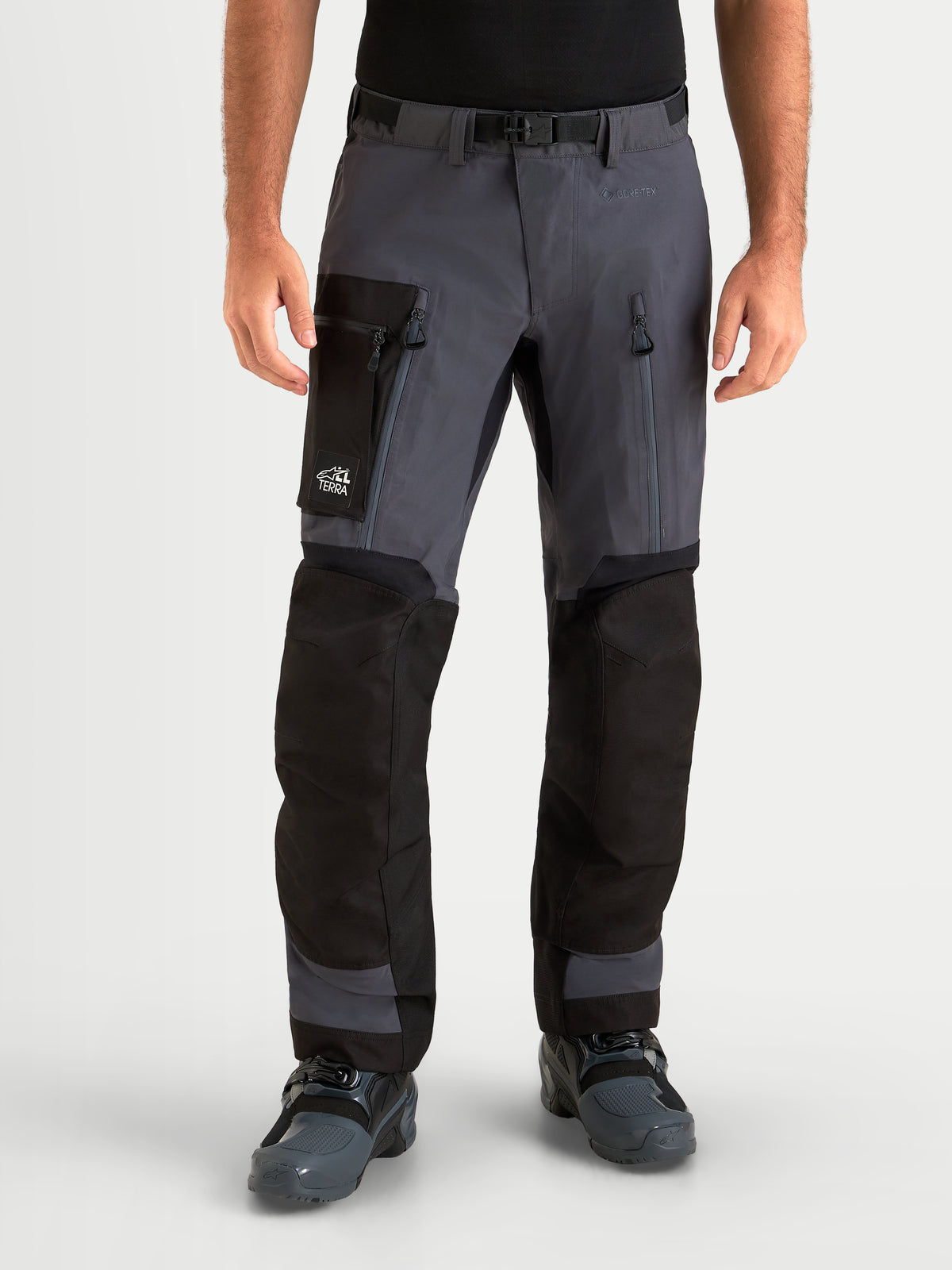 Alpinestars Pantaloni Arenis Gore-Tex, pantaloni da moto adventure da uomo, grigio scuro e nero, vista frontale su un modello con tasche cargo e prese d'aria sulle cosce