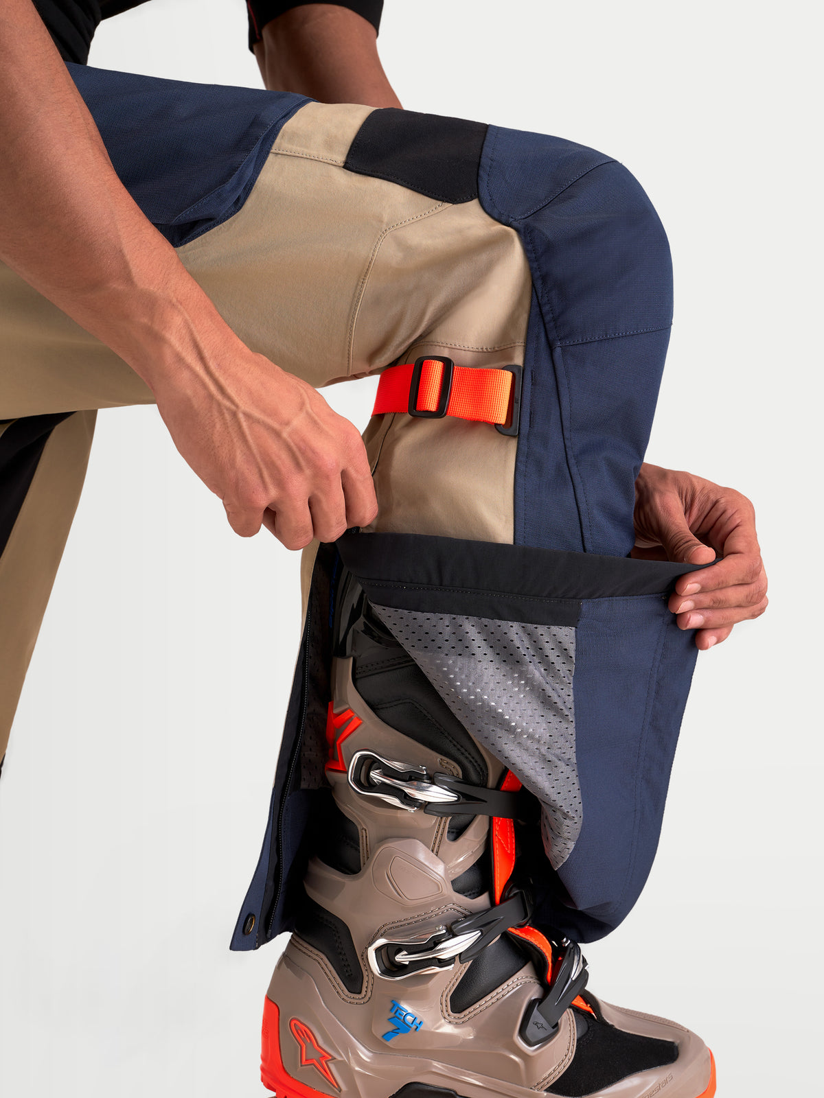 Alpinestars Arenis Gore-Tex Pantaloni, pantaloni da moto adventure da uomo in blu navy e alluminio, dettaglio ravvicinato di un modello che regola la cerniera della gamba inferiore sopra uno stivale adventure, costruzione impermeabile in tessuto