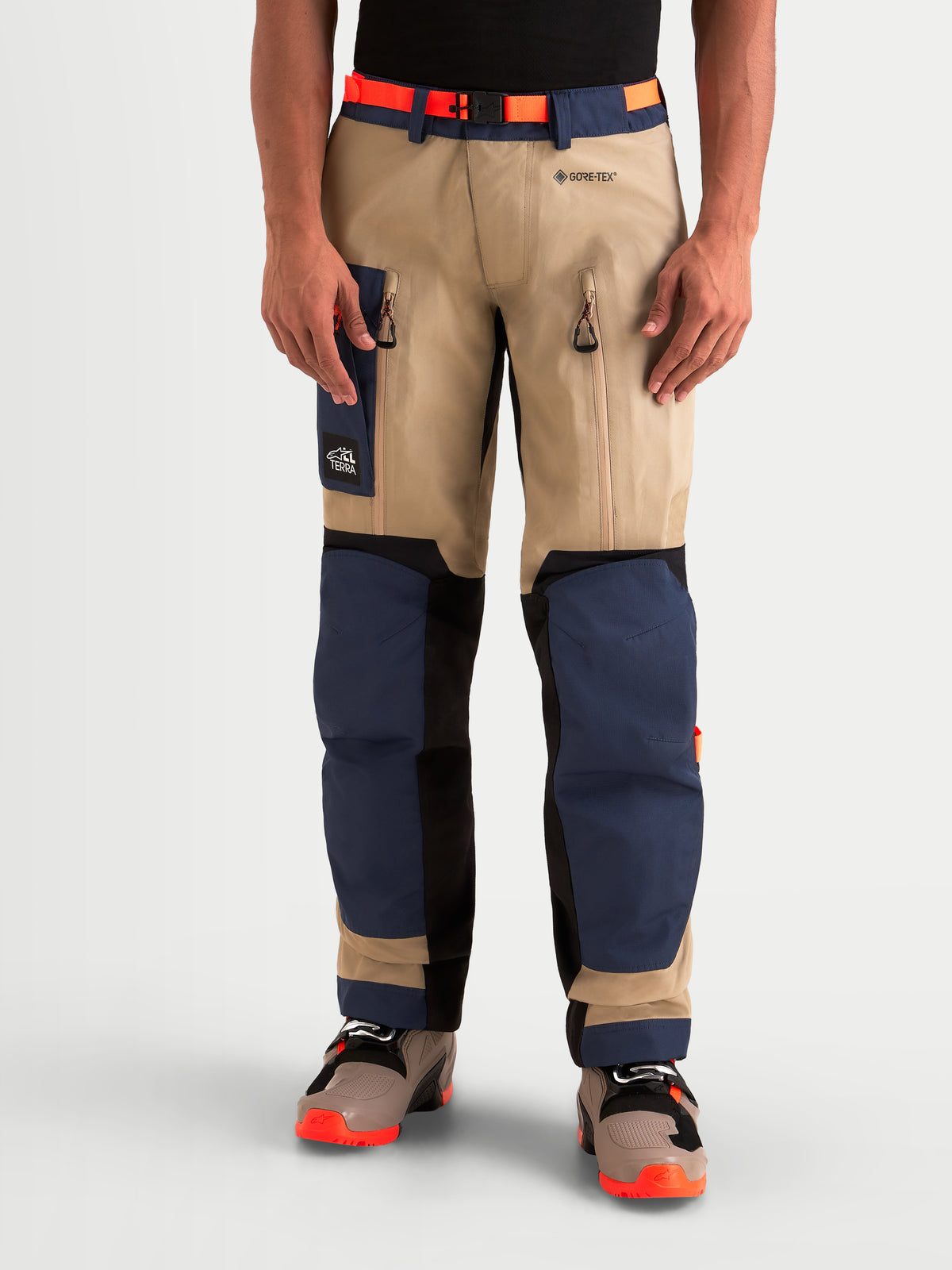 Alpinestars Arenis Gore-Tex Pantaloni, pantaloni da moto adventure da uomo in blu navy e beige, vista anteriore su un modello che indossa attrezzatura da guida impermeabile con ventilazione sulle cosce e protezione rinforzata per le ginocchia