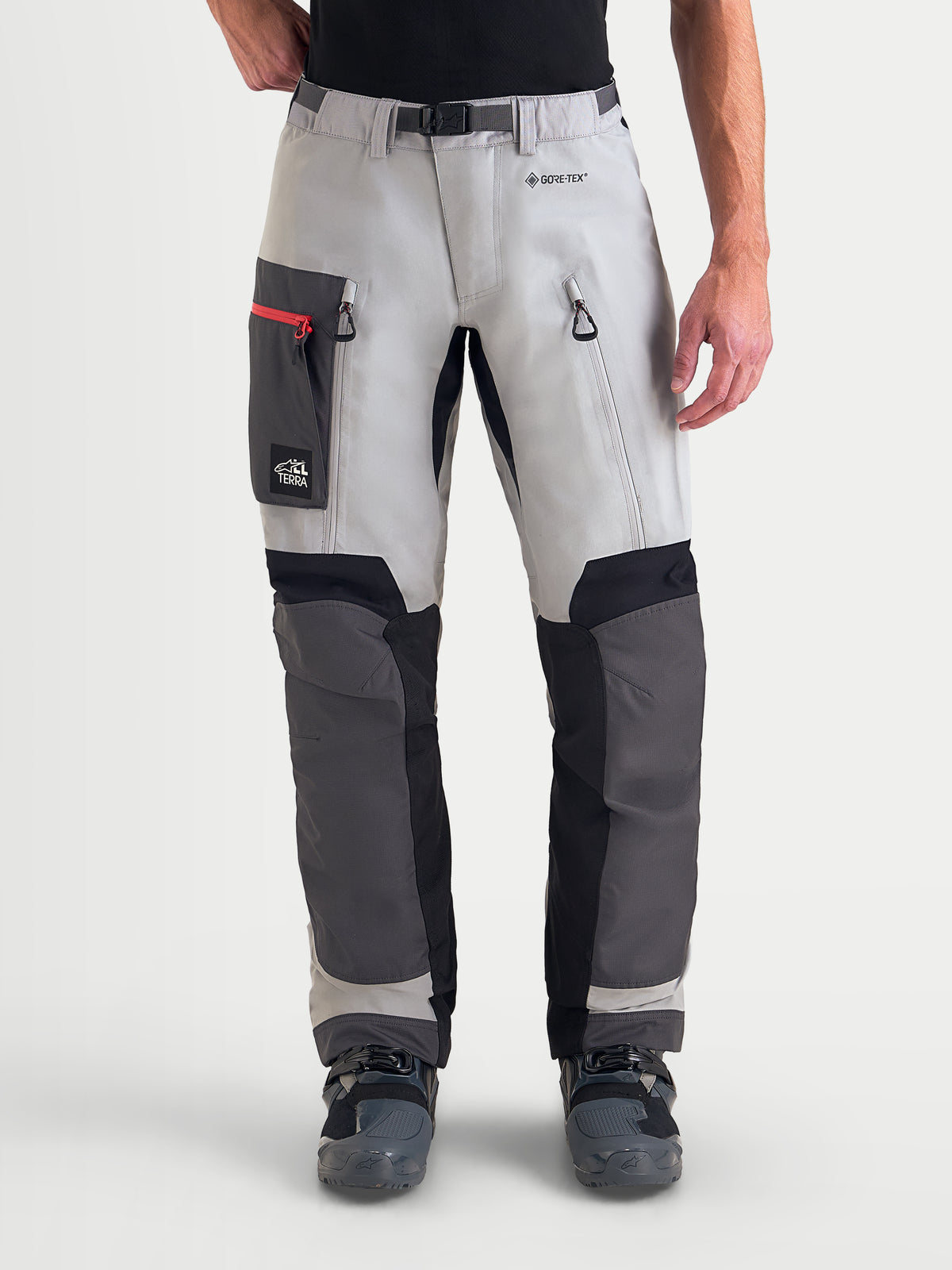 Alpinestars Arenis Gore-Tex Pantaloni, pantaloni da moto adventure da uomo in grigio medio, grigio scuro e nero, vista anteriore su un modello con tasche sulle cosce e cerniere di ventilazione