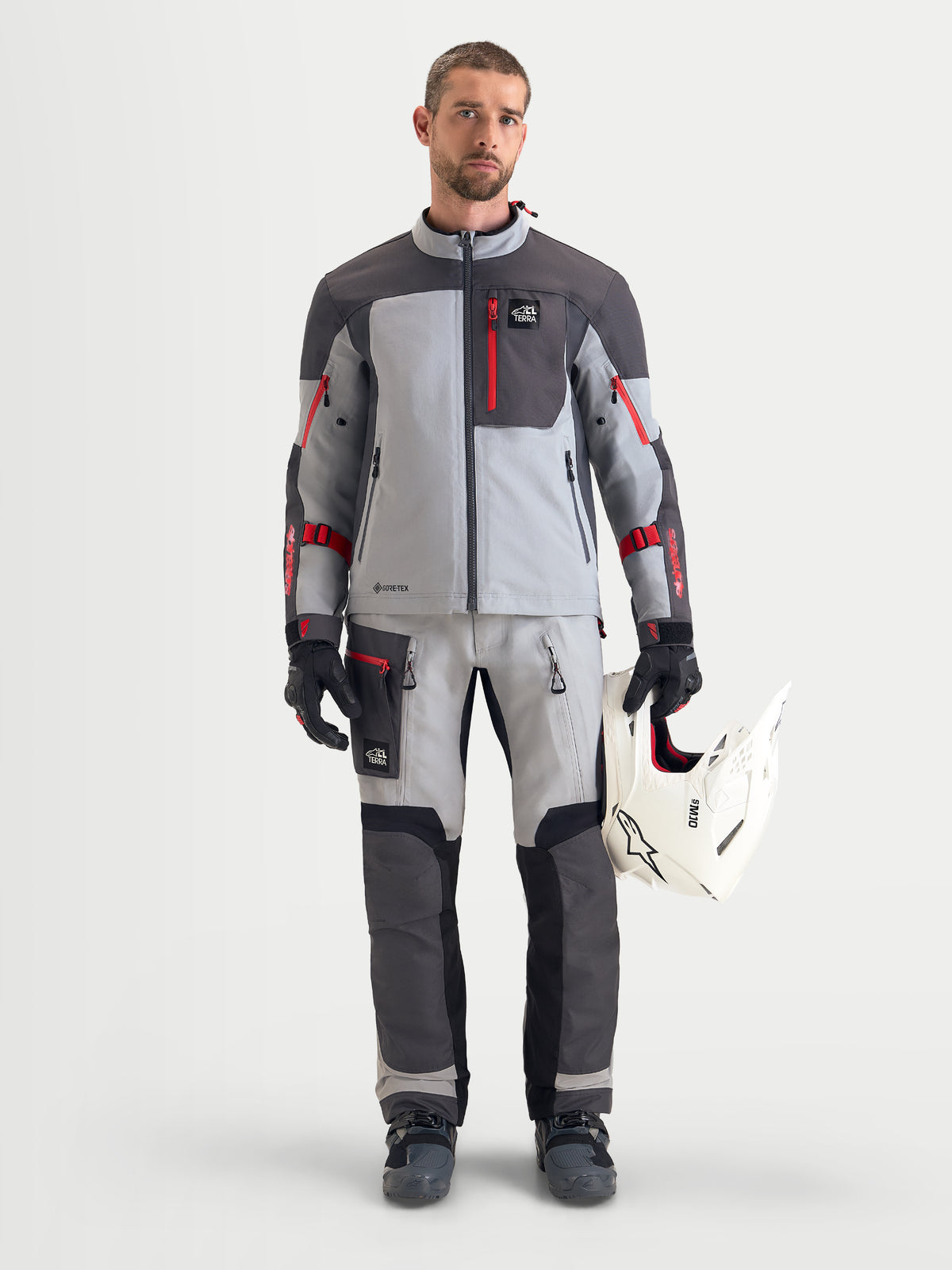 Alpinestars Arenis Gore-Tex Pantaloni, pantaloni da moto adventure da uomo in grigio chiaro, grigio scuro e nero, vista frontale su un modello che indossa una giacca abbinata e un casco bianco