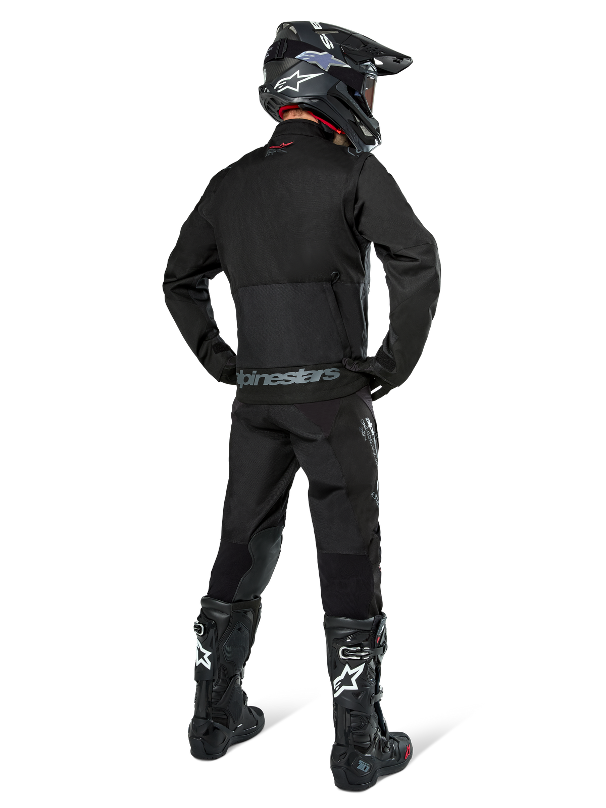 Giacca Alpinestars Pro-Dura, giacca da enduro off-road nera, vista posteriore indossata con pantaloni coordinati e stivali Tech 10 neri, caratterizzata dal prominente logo Alpinestars sulla parte bassa della schiena, costruzione in tessuto robusto per guida trail aggressiva
