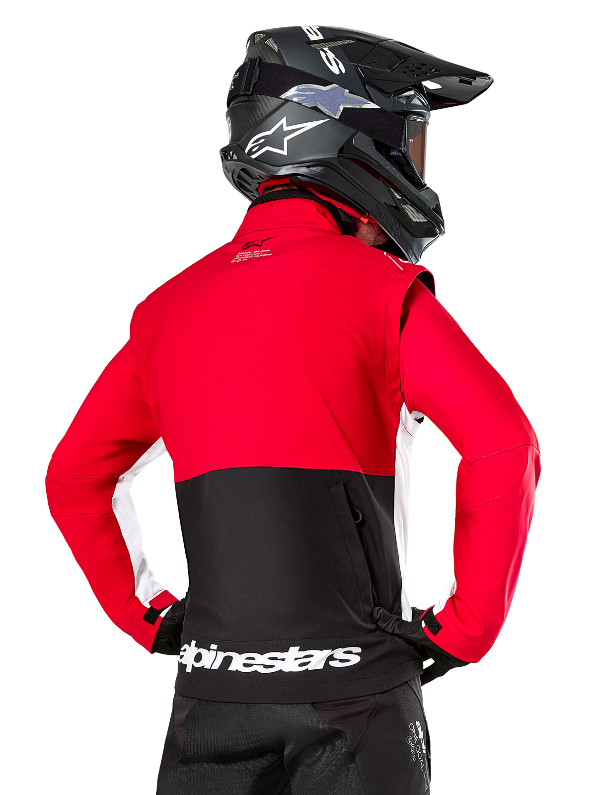 Alpinestars Lite-Dura Softshell Jacket, nero, rosso brillante e bianco, vista posteriore su un pilota di motocross, parte superiore e maniche rosse con pannello posteriore inferiore nero, tasca posteriore portaoggetti con zip, logo Alpinestars bianco sull'orlo inferiore, indossata con casco e pantaloni neri.