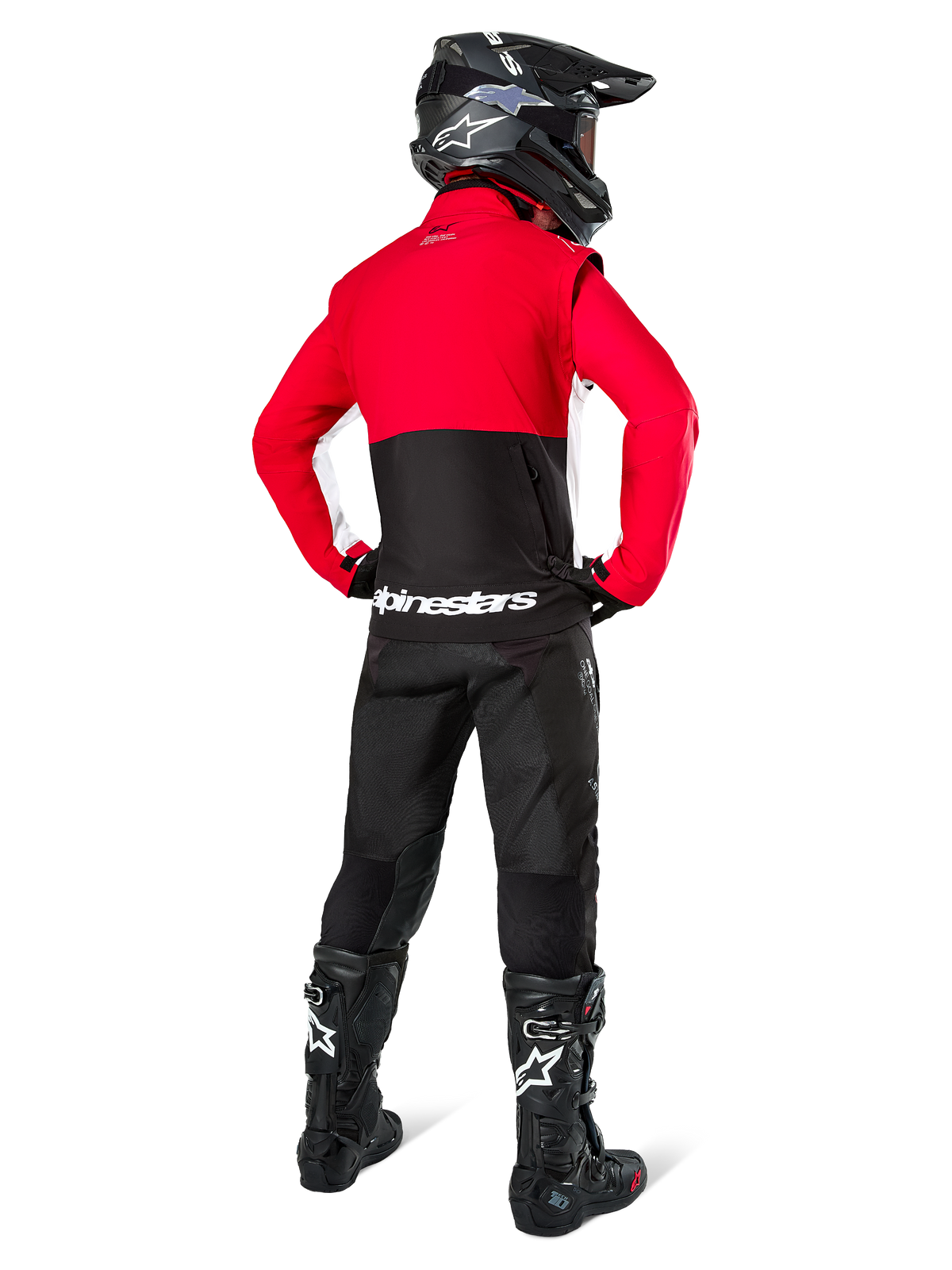 Pilota di motocross da dietro con giacca Softshell Alpinestars Lite-Dura, nero rosso acceso e bianco, con pannello superiore rosso e sezione inferiore nera con branding bianco, abbinata a pantaloni neri, casco nero e stivali neri, completo da enduro coordinato per guida off-road