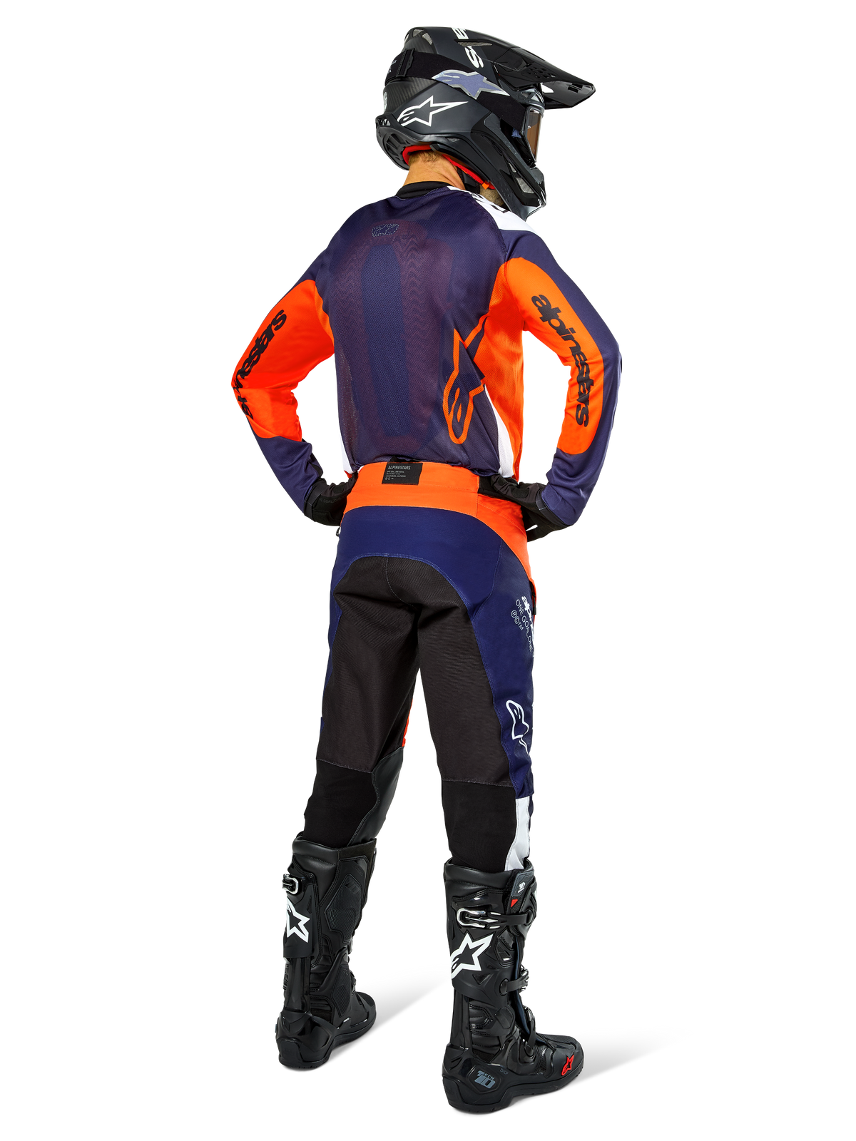Pilota di motocross con abbigliamento da gara completo visto di spalle, maglia blu navy e arancione, pantaloni Pro-Dura in Navy Hot Orange White, casco e stivali neri, completo professionale da corsa off-road.