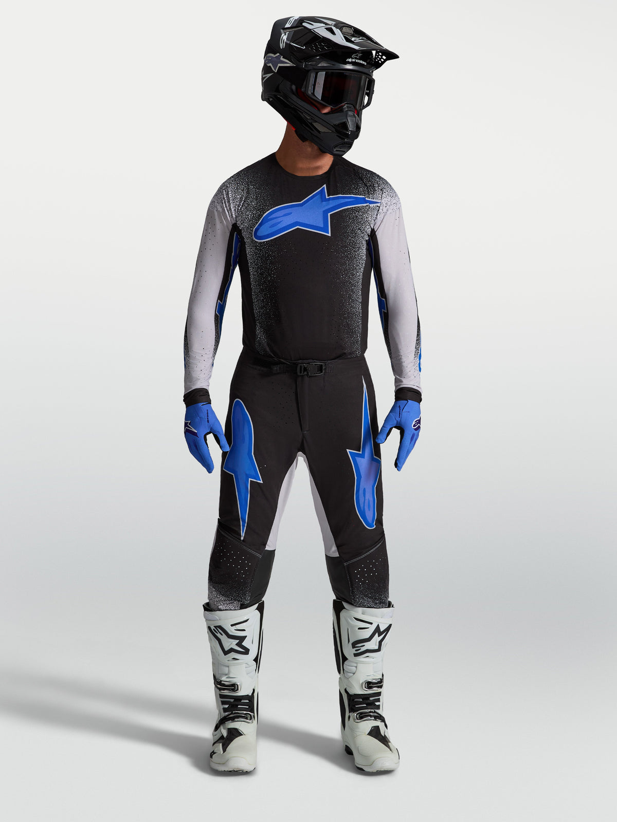 Alpinestars pantaloni Supertech Hiten AFD, pantaloni da motocross da uomo neri e blu, indossati con maglia coordinata e stivali da corsa bianchi per fuoristrada pro racing