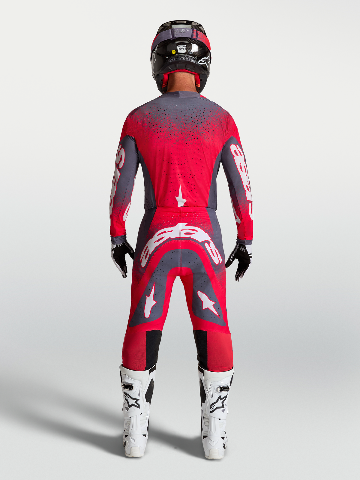 Alpinestars Supertech Hiten AFD Gear Set e Pantaloni, completo da motocross professionale, rosso fluo e grigio, vista posteriore su modello, equipaggiamento racing per fuoristrada.