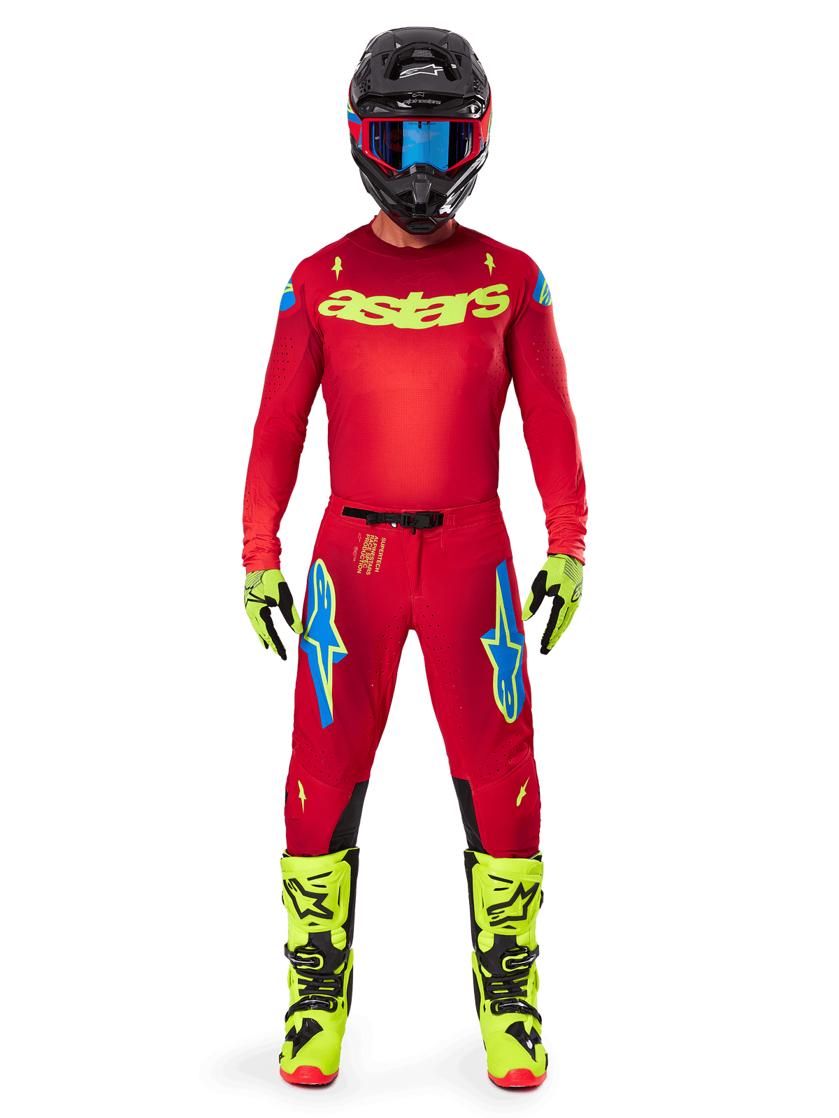 Pilota di motocross con abbigliamento completo da gara, maglia rossa con logo astars giallo fluo, pantaloni Alpinestars 2025 Supertech Maker in Rosso Brillante e Giallo Fluo con loghi blu sulle cosce, guanti e stivali giallo fluo, casco nero con occhiali blu, outfit coordinato da motocross professionale.